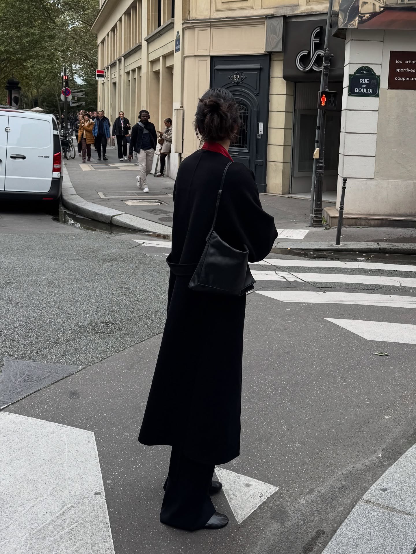 Kendall Jenner stands on a road in New York wearing a black wool coat, black trousers and rounded-toe shoes