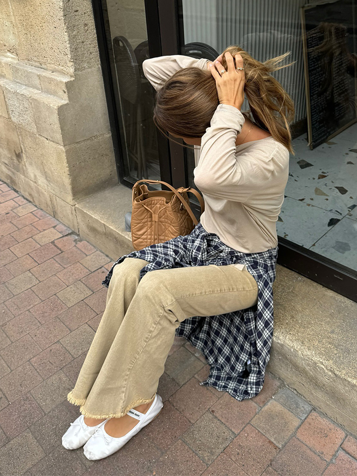 anne wears long sleeve t shirt, tan jeans, white ballet flats, and a plaid button down shirt around the waist