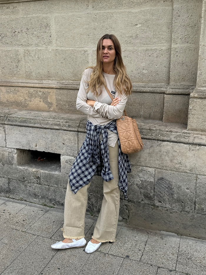 anne wears long sleeve t shirt, tan jeans, white ballet flats, and a plaid button down shirt around the waist