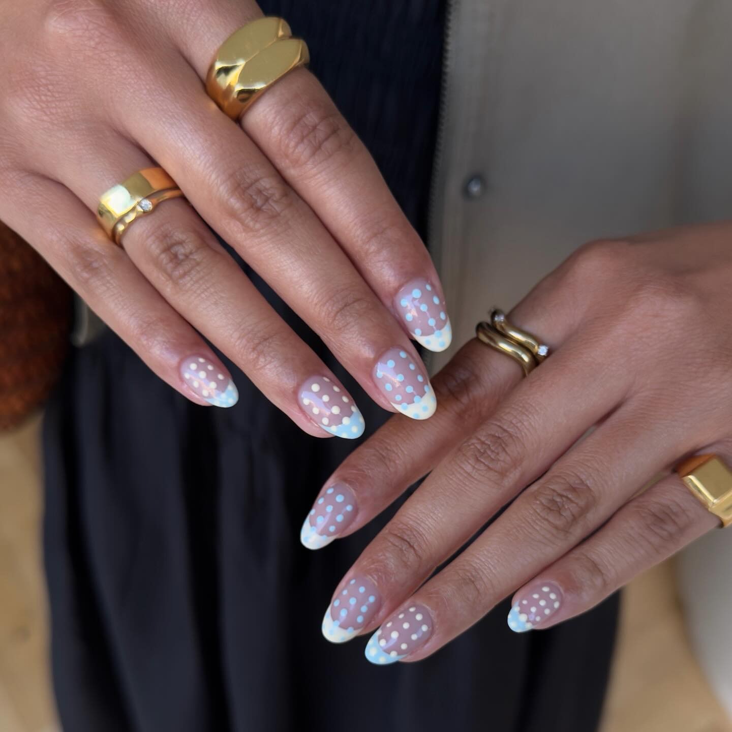 A French tip manicure with a polka dot design layered over the top