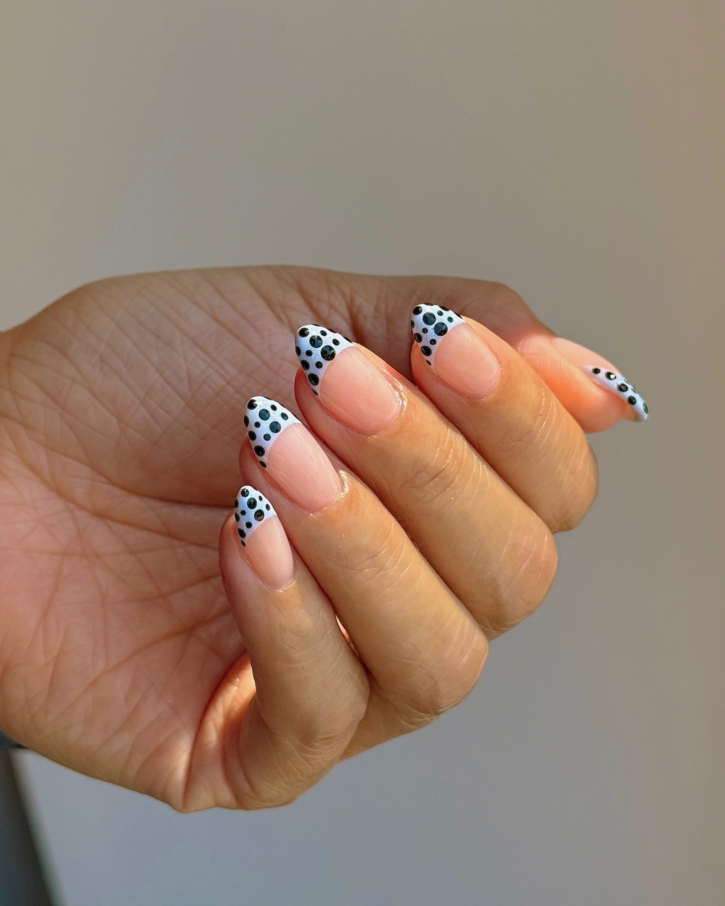A blue French tip nail design with black polka dots