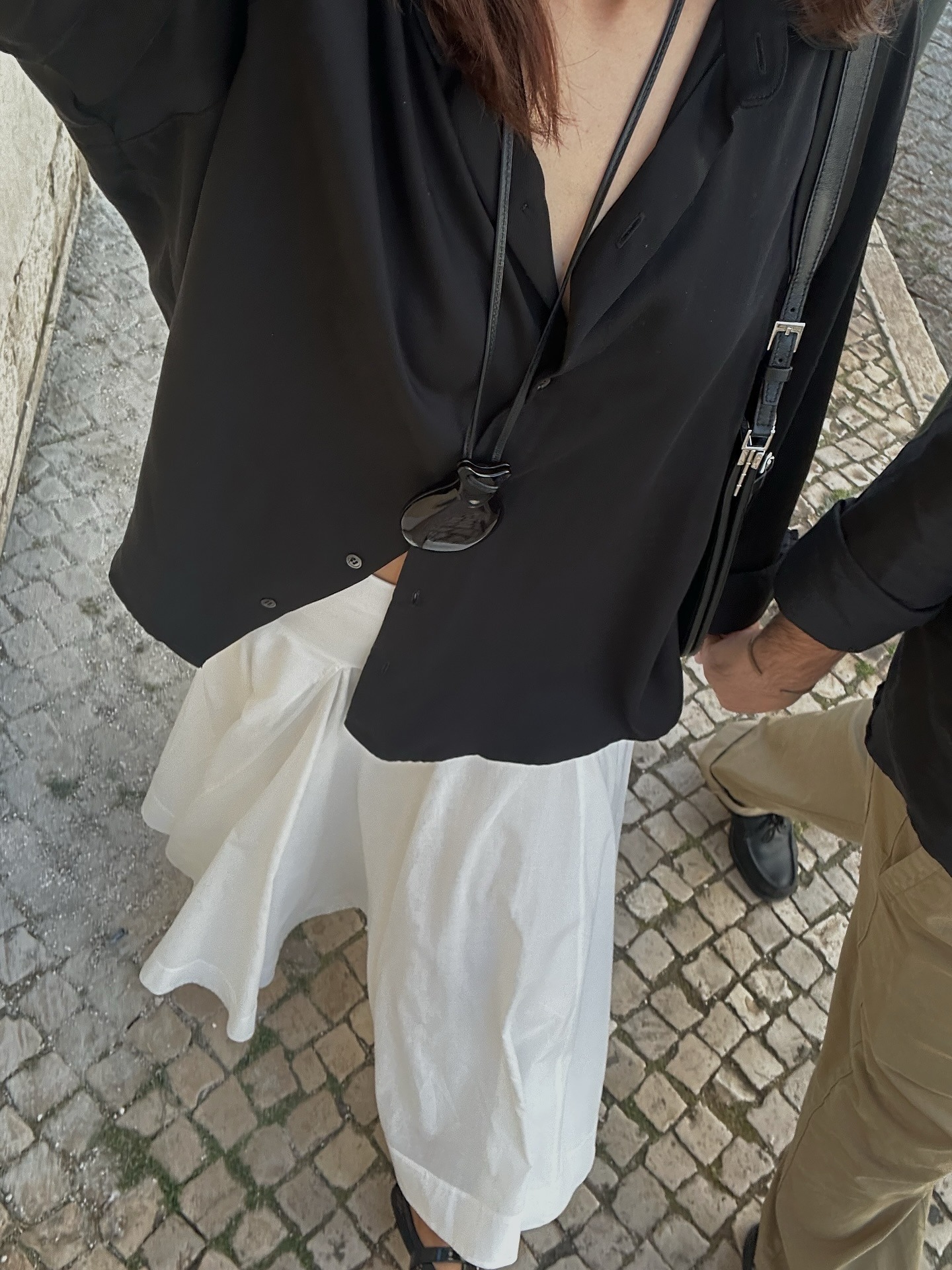Influencer @deborabrosa wears a black satin blouse with a white skirt.