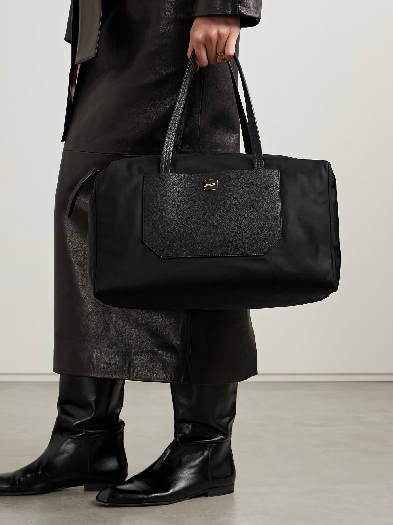 A woman wearing a black Khaite weekend bag