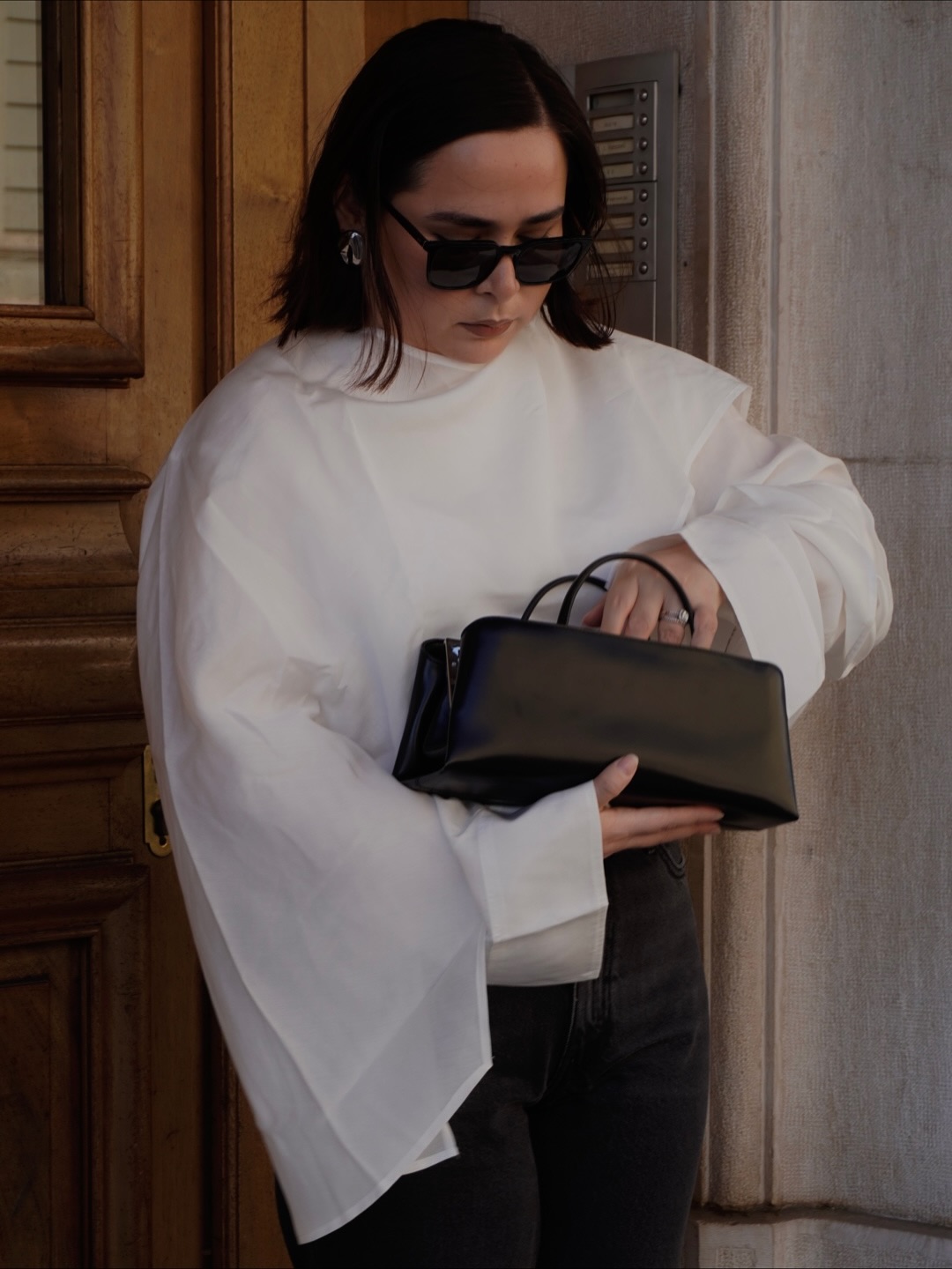 Influencer Indira C wearing a white blouse and mini clutch bag