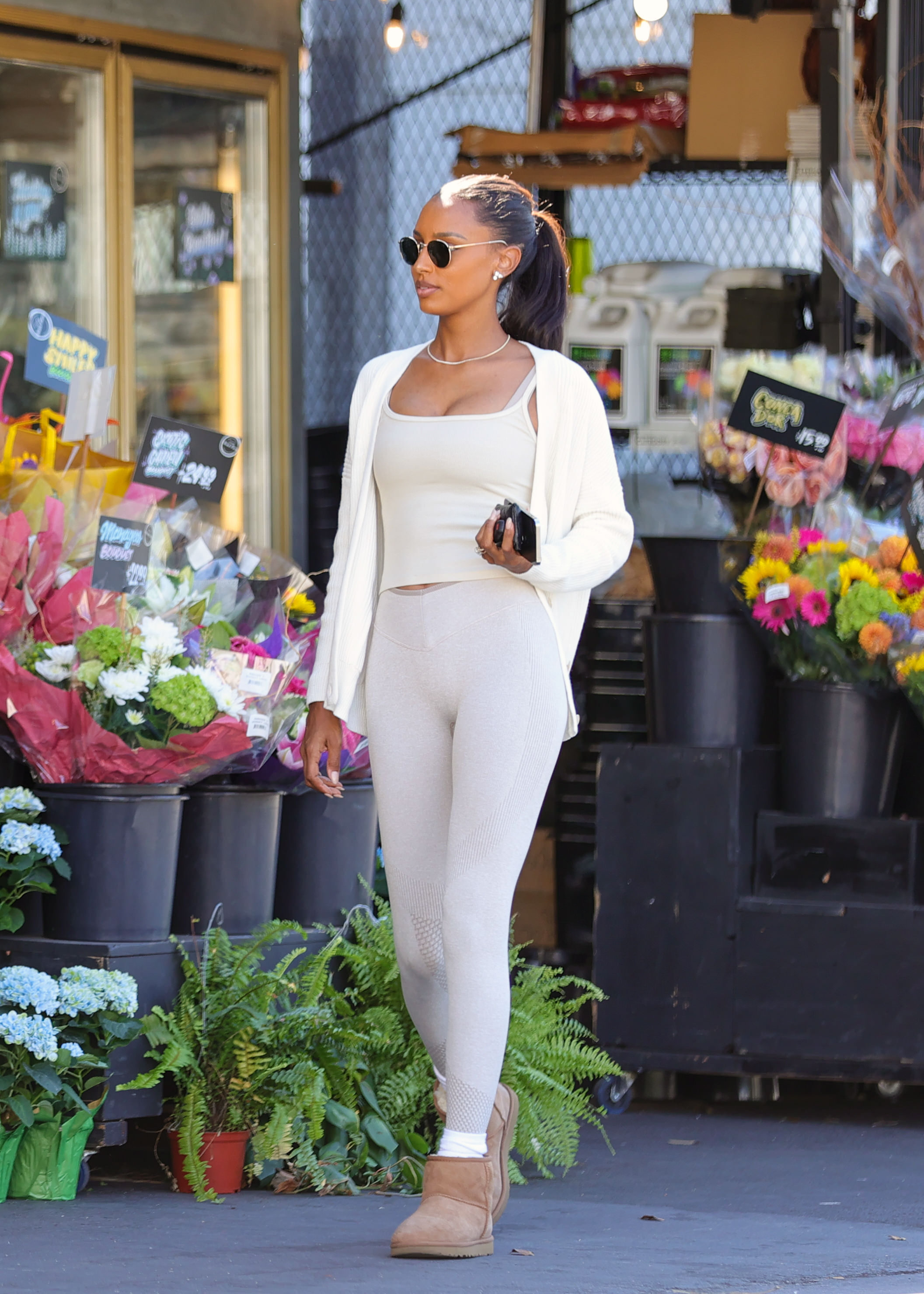 Jasmine Tookes wears a white tank, cardigan, leggings, and Uggs.