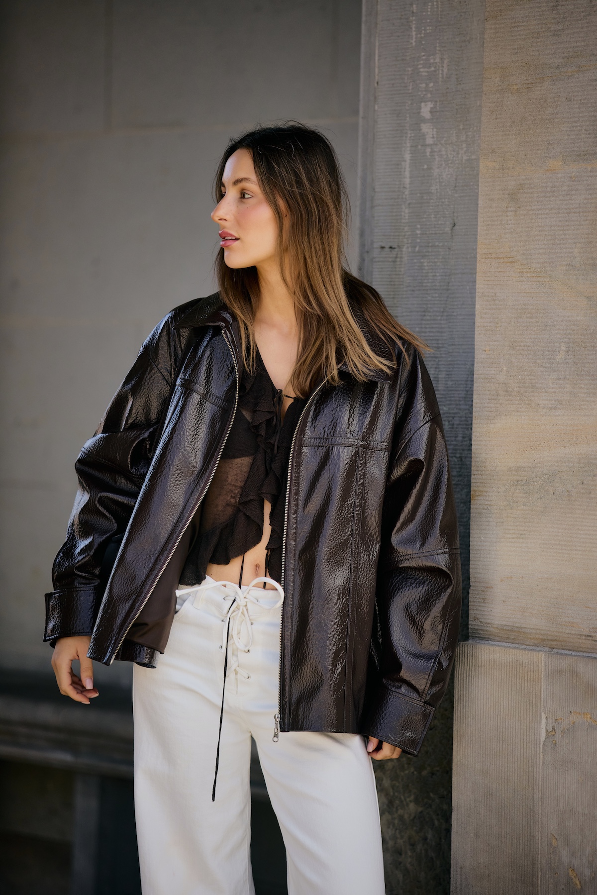 street style shot from The Style Stalker brown bomber jacket sheer black top, and lace-up white jeans
