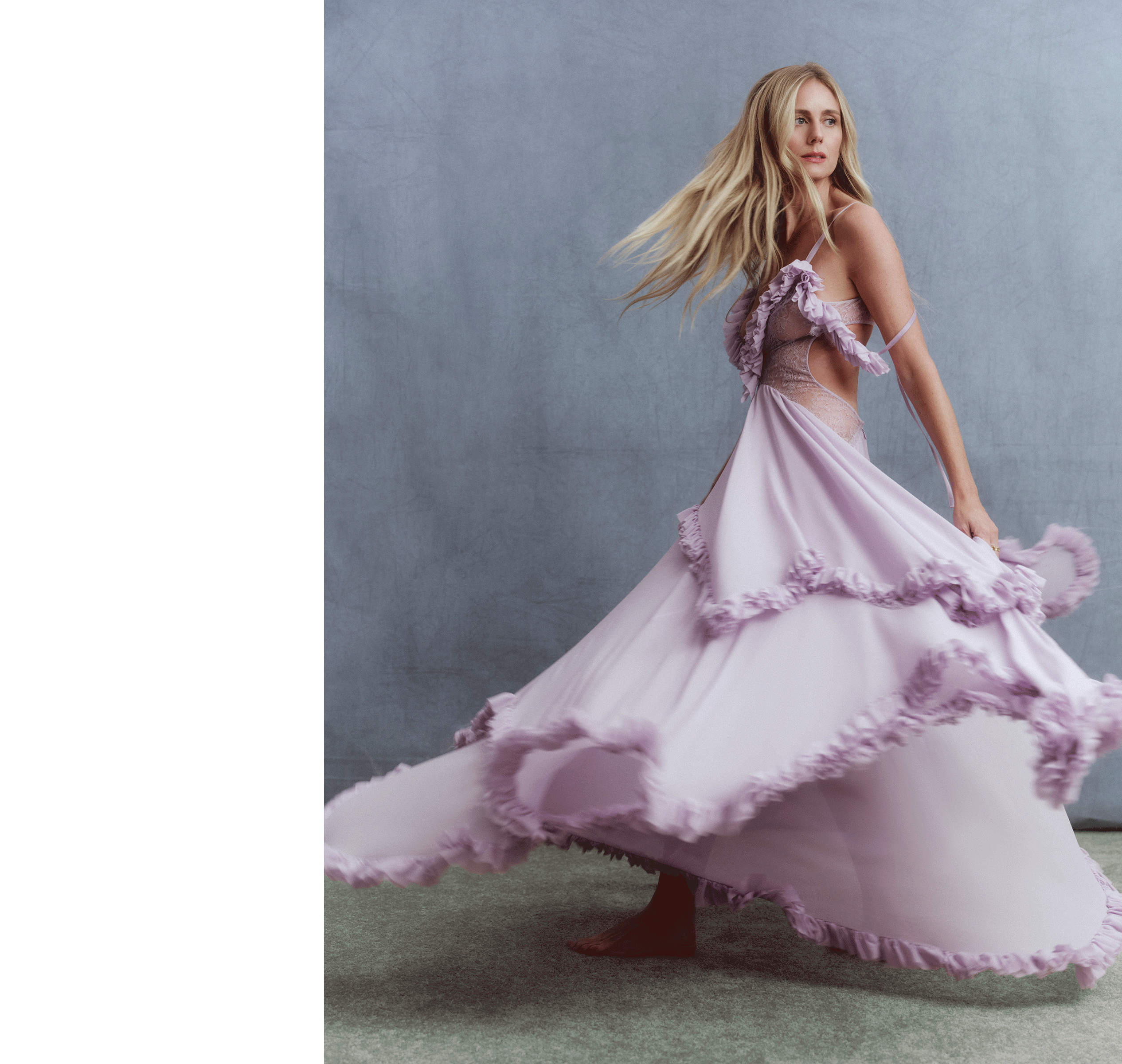 Justine Lupe twirling wearing a McQueen purple dress in front of a gray background.