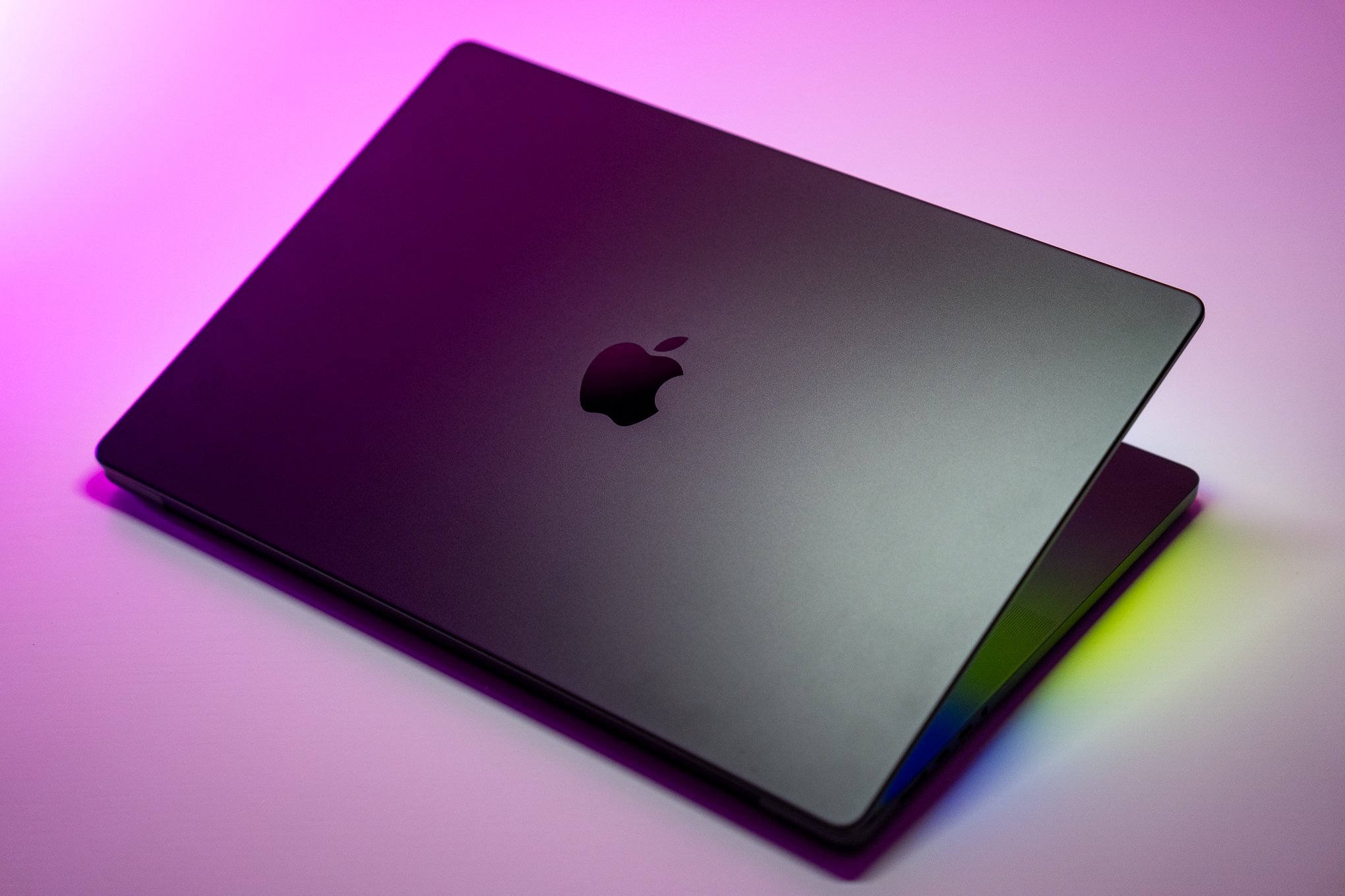 The 16-inch MacBook Pro with M4 Max chip on a white table with pink background.