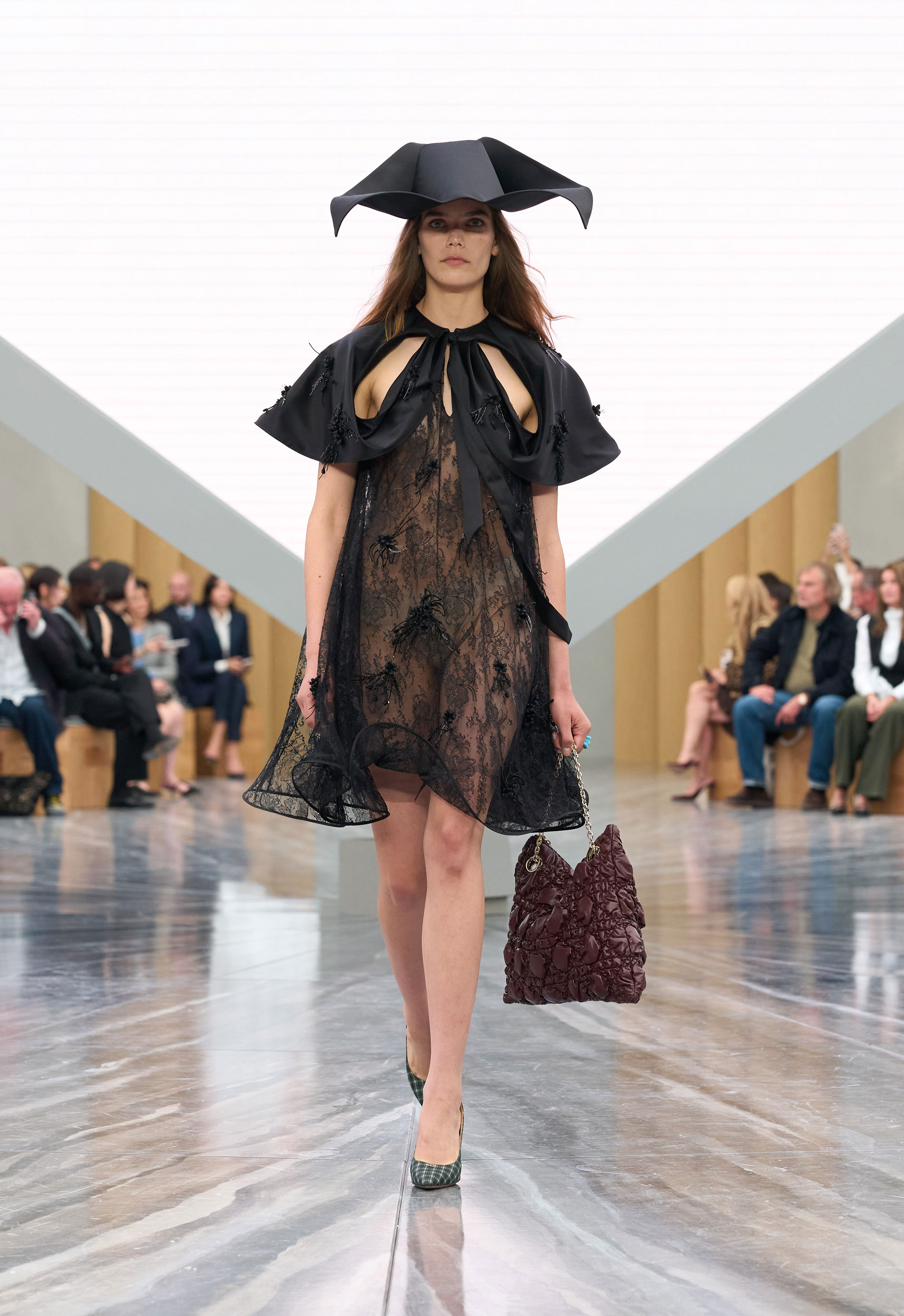 a runway model wears a black lace dress by Dior