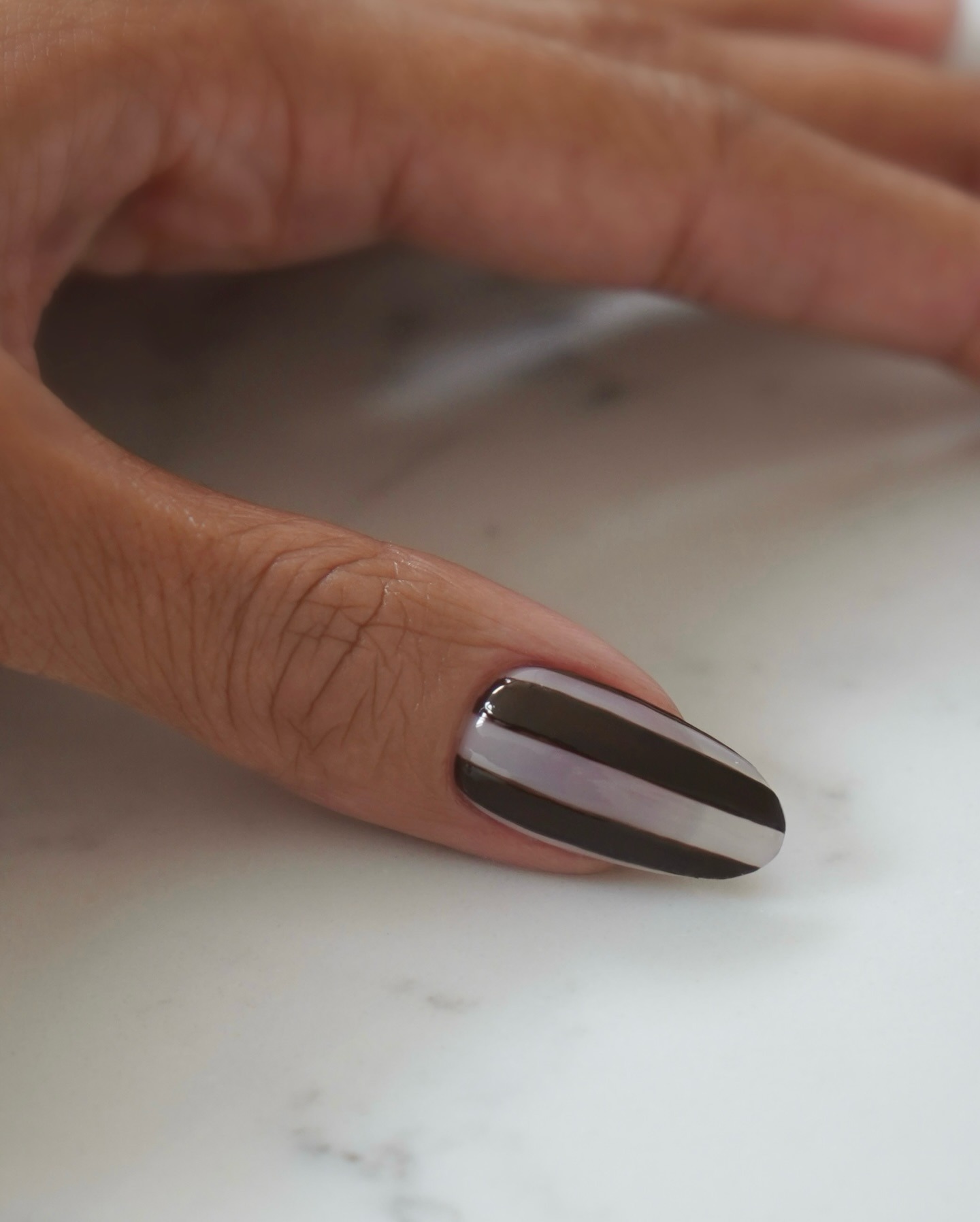 A close-up picture of a brown stripe nail design