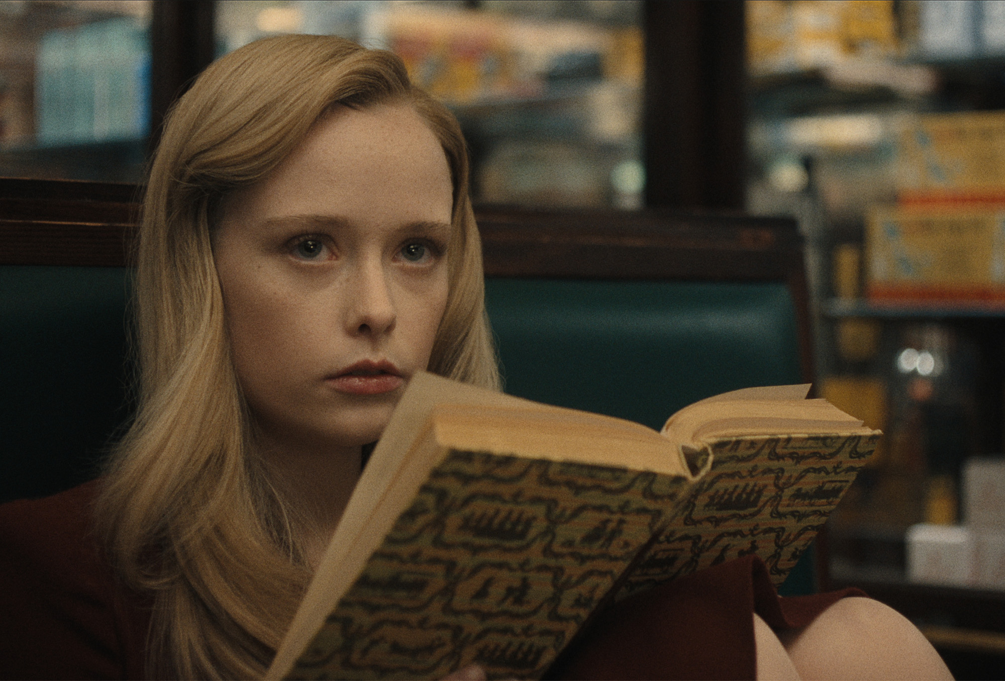 Still from Netflix&#039;s Monster: The Ed Gein Story of the character Adeline Watkins, played by Suzanna Son, reading a book.