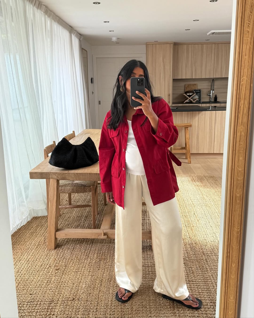 @monikh wearing red barn jacket and silk pants