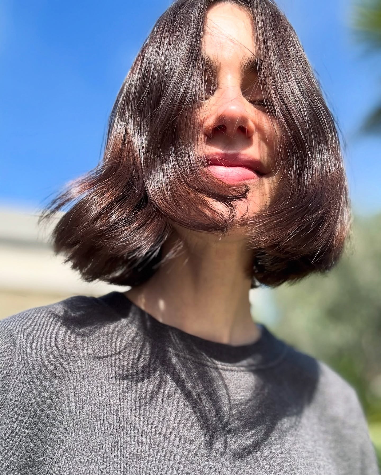 Lily Collins with a short, shiny brunette bob