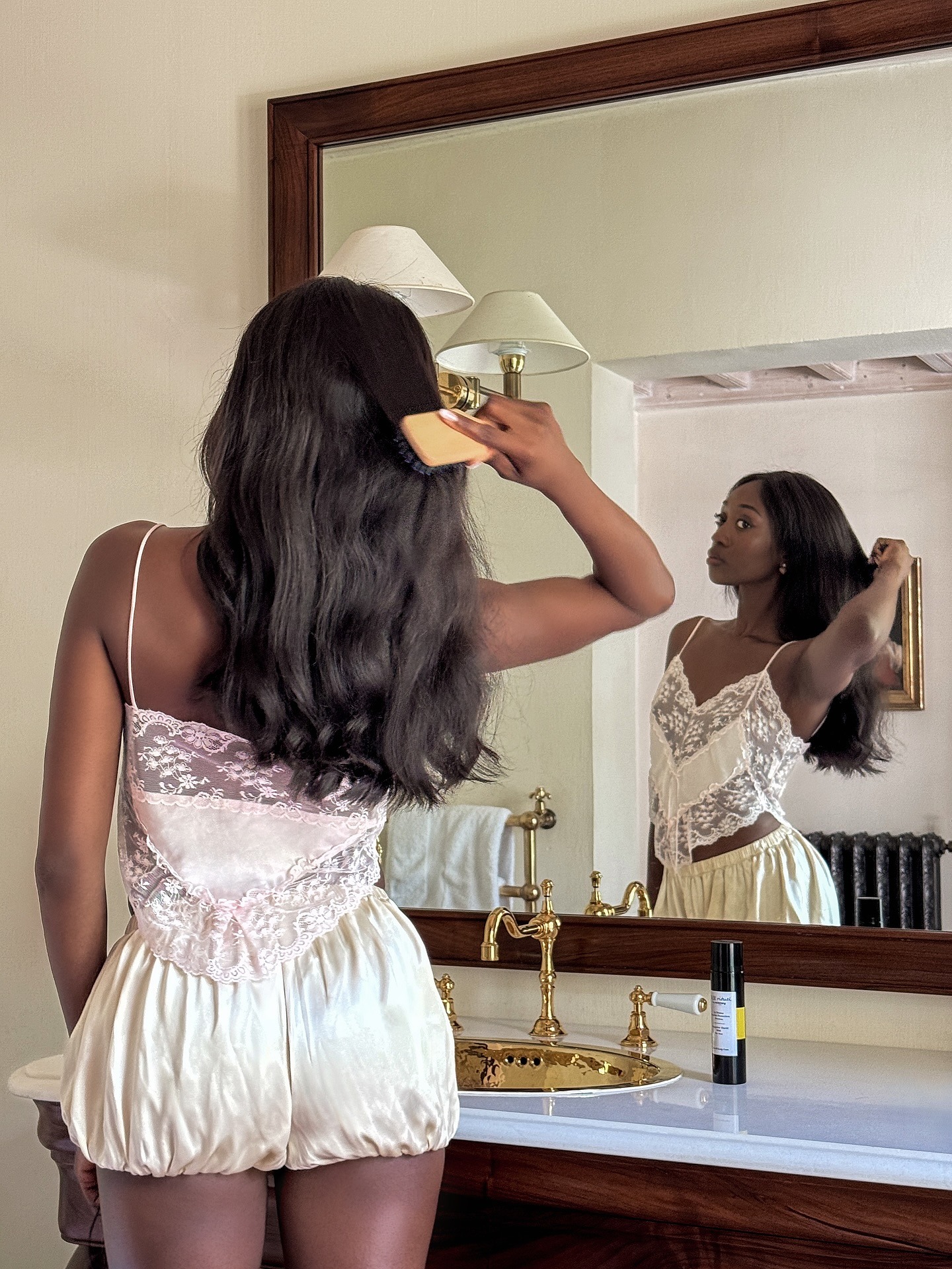 A woman brushing her hair in the mirror with shiny brunette hair