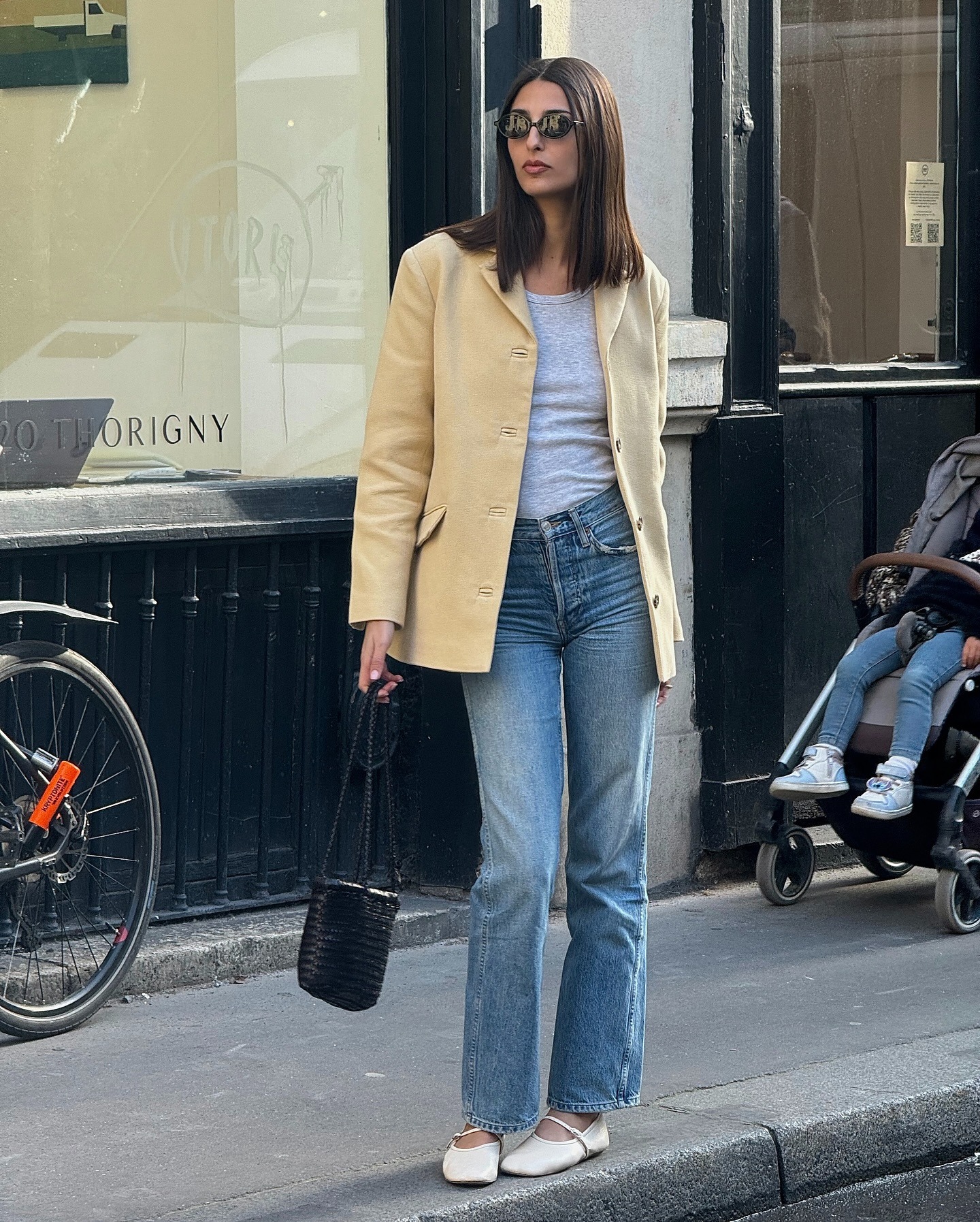 A woman standing on the pavement in Paris wearing a suede jacket with shiny brunette hair