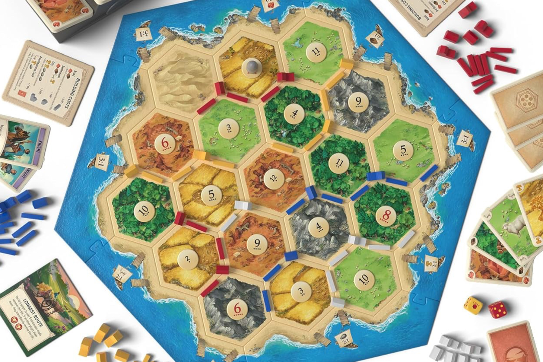 An overhead shot of a Catan board game including pieces and cards.