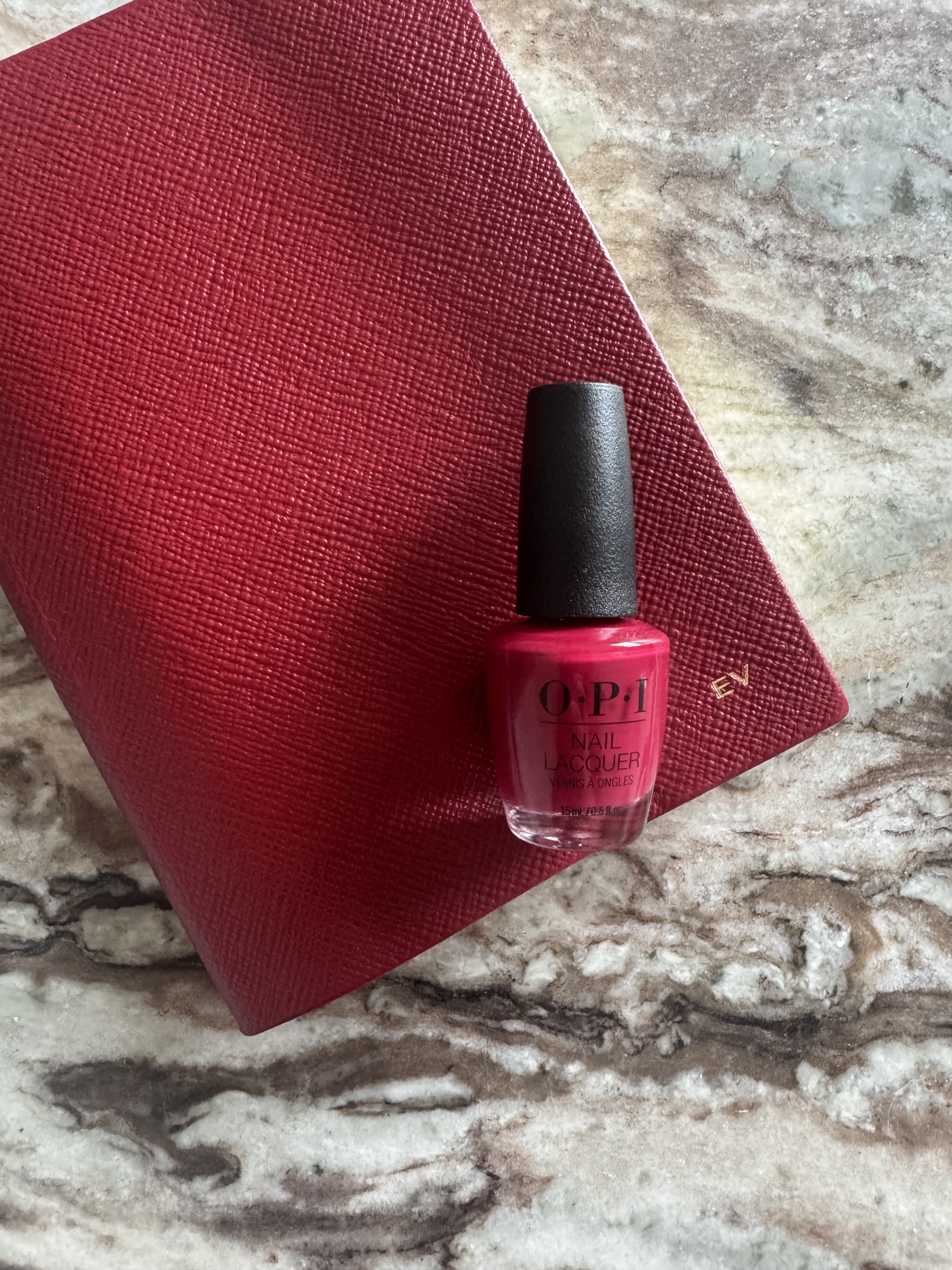 OPI Malaga Wine nail polish bottle resting on a red notebook
