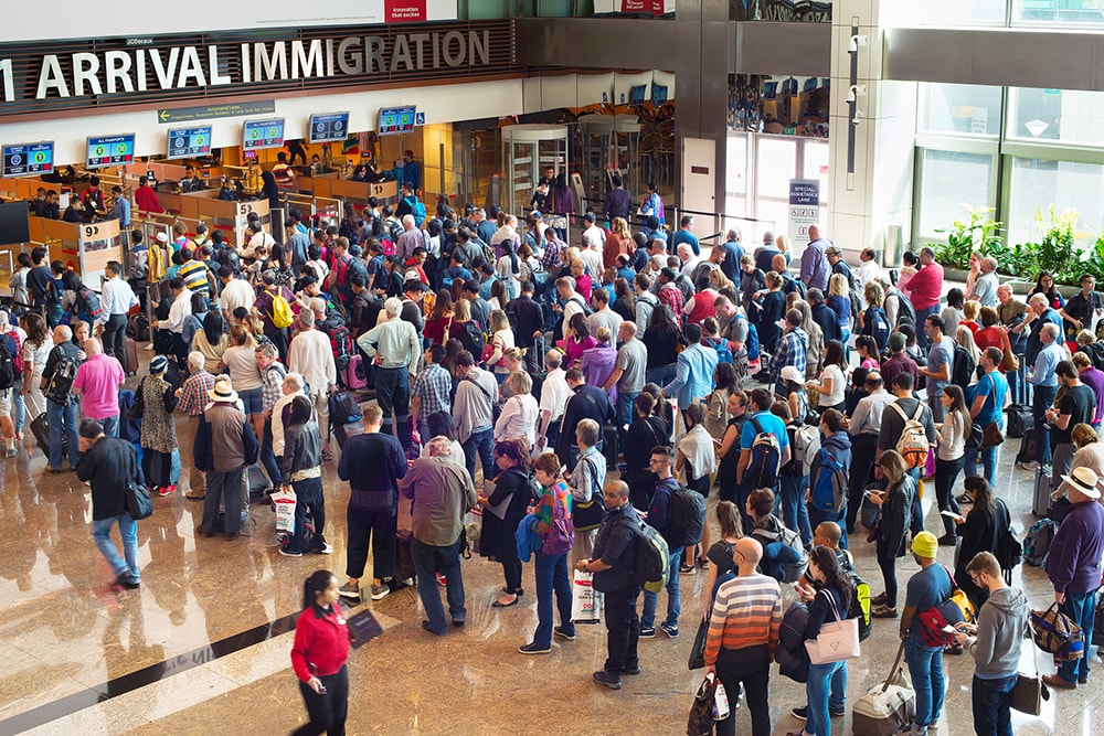 crowds of people waiting at airport immigration 
