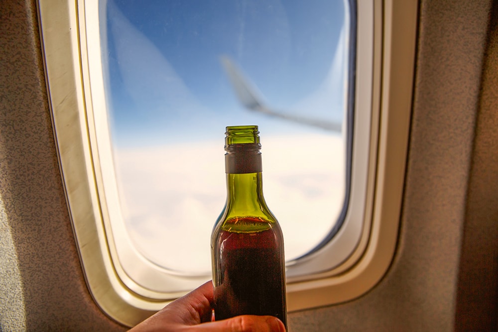A bottle of wine opposite the porthole on a plane