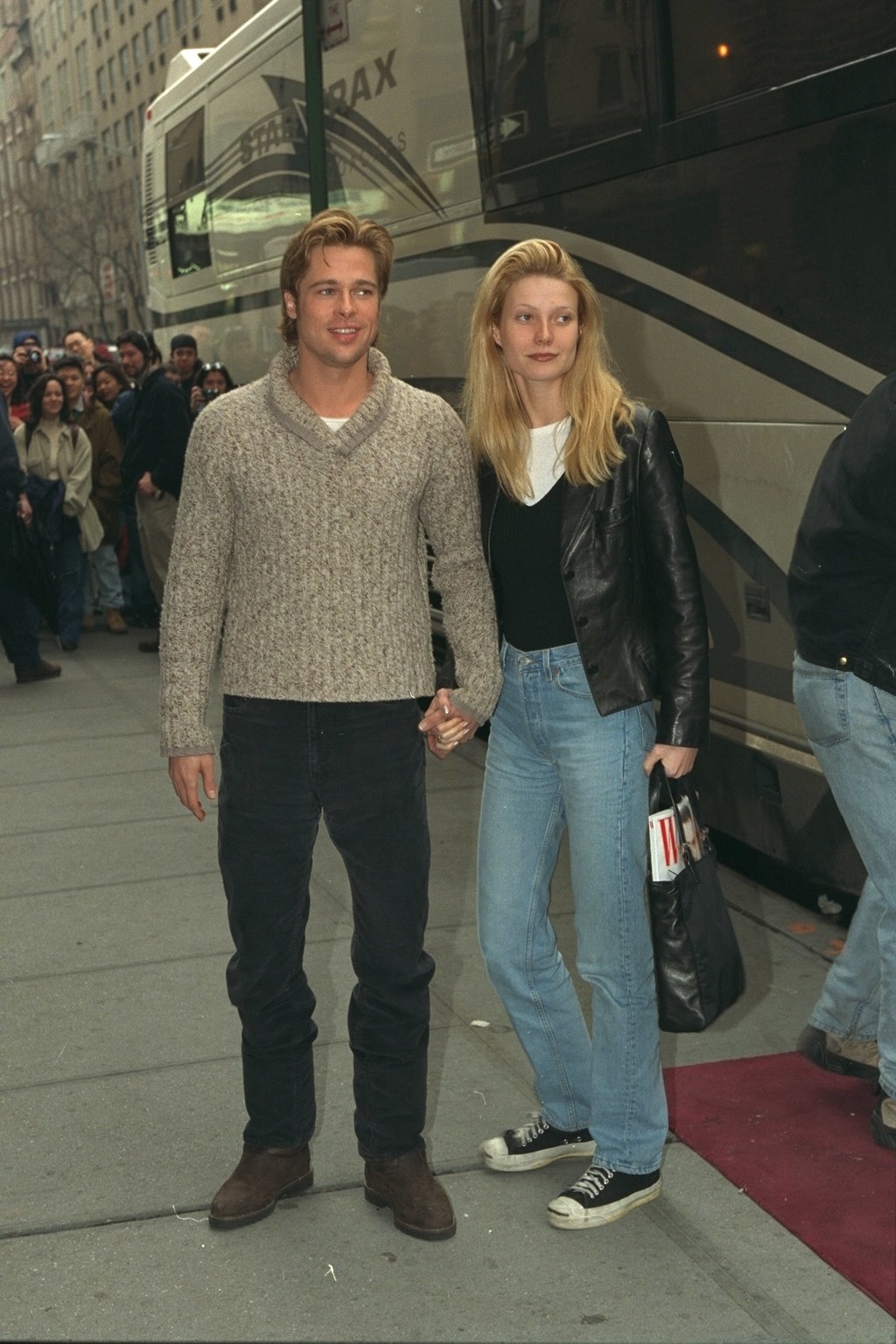 Image of Gwyneth Paltrow in the &#039;90s wearing a v-neck jumper over a white t-shirt with blue jeans and black converse.