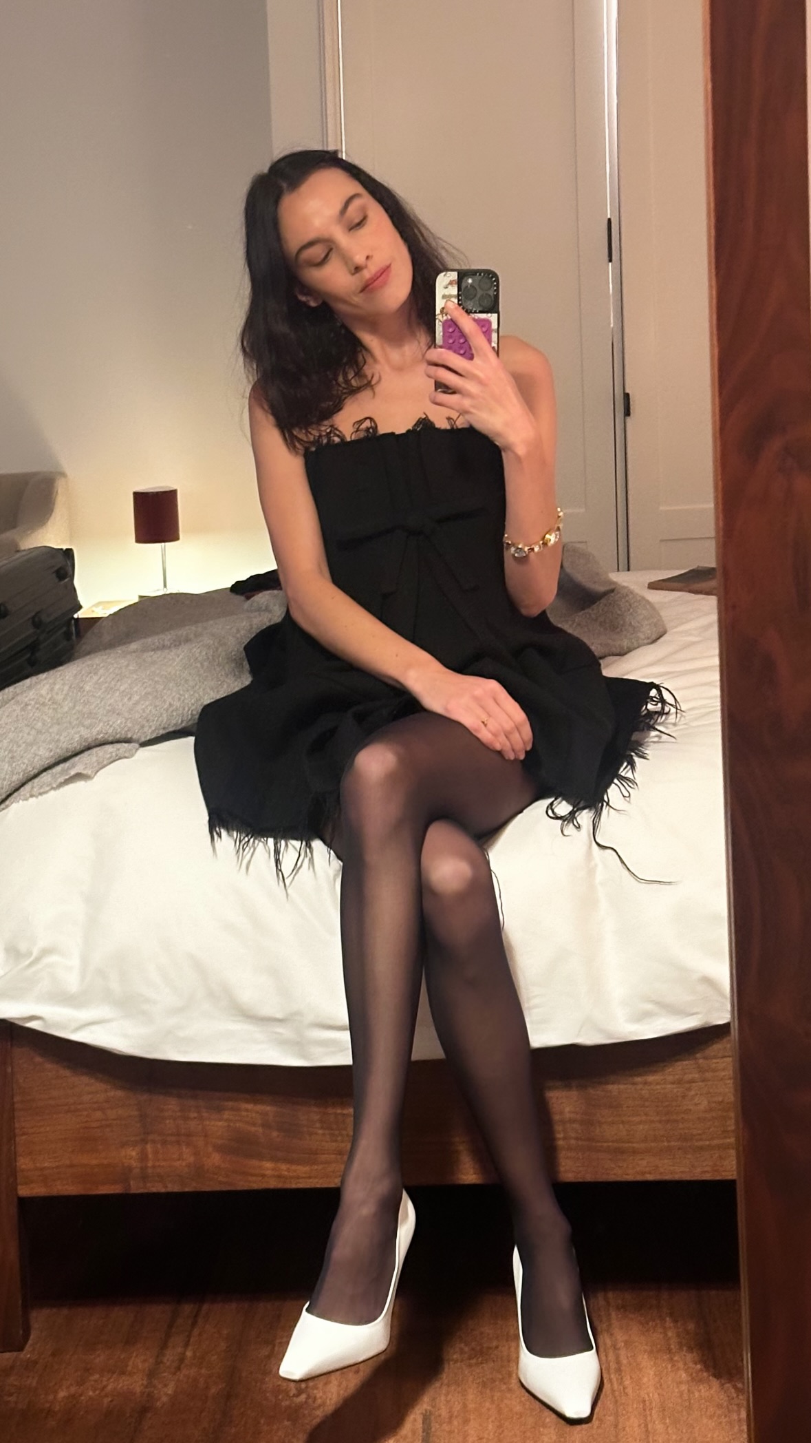 An image of @alexachung wearing a little black dress with black tights and white heels.