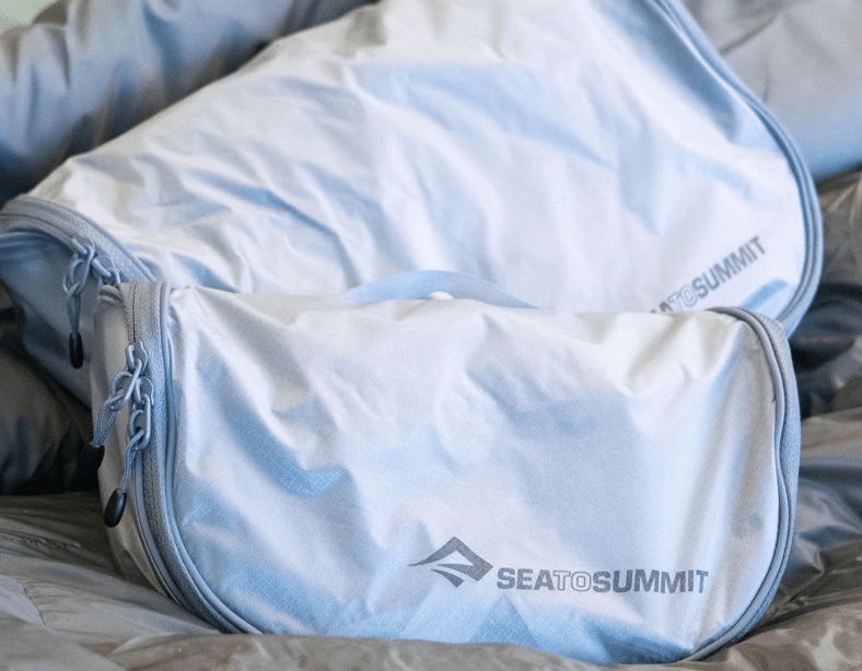 The large and small versions of the Sea to Summit Hanging Toiletry Bag sitting on a seat.