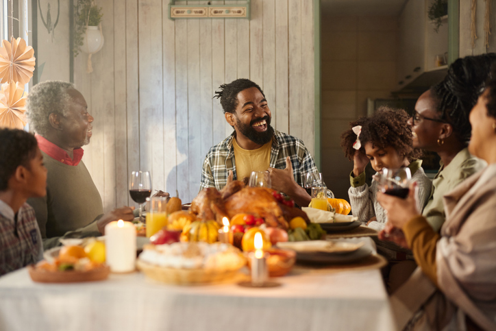 Happy black extended family talking during Thanksgiving lunch in dining room.