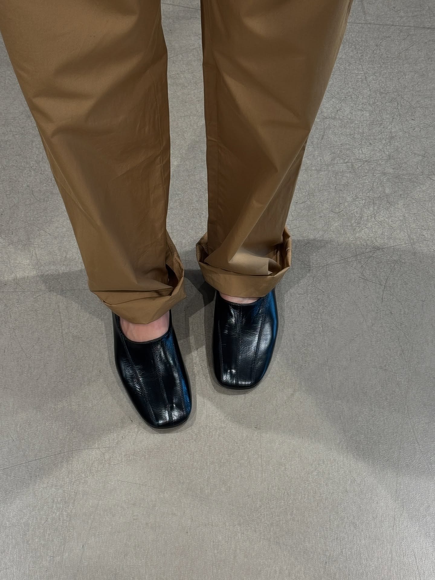 A woman wears khaki pants with black eel high-vamp heels.