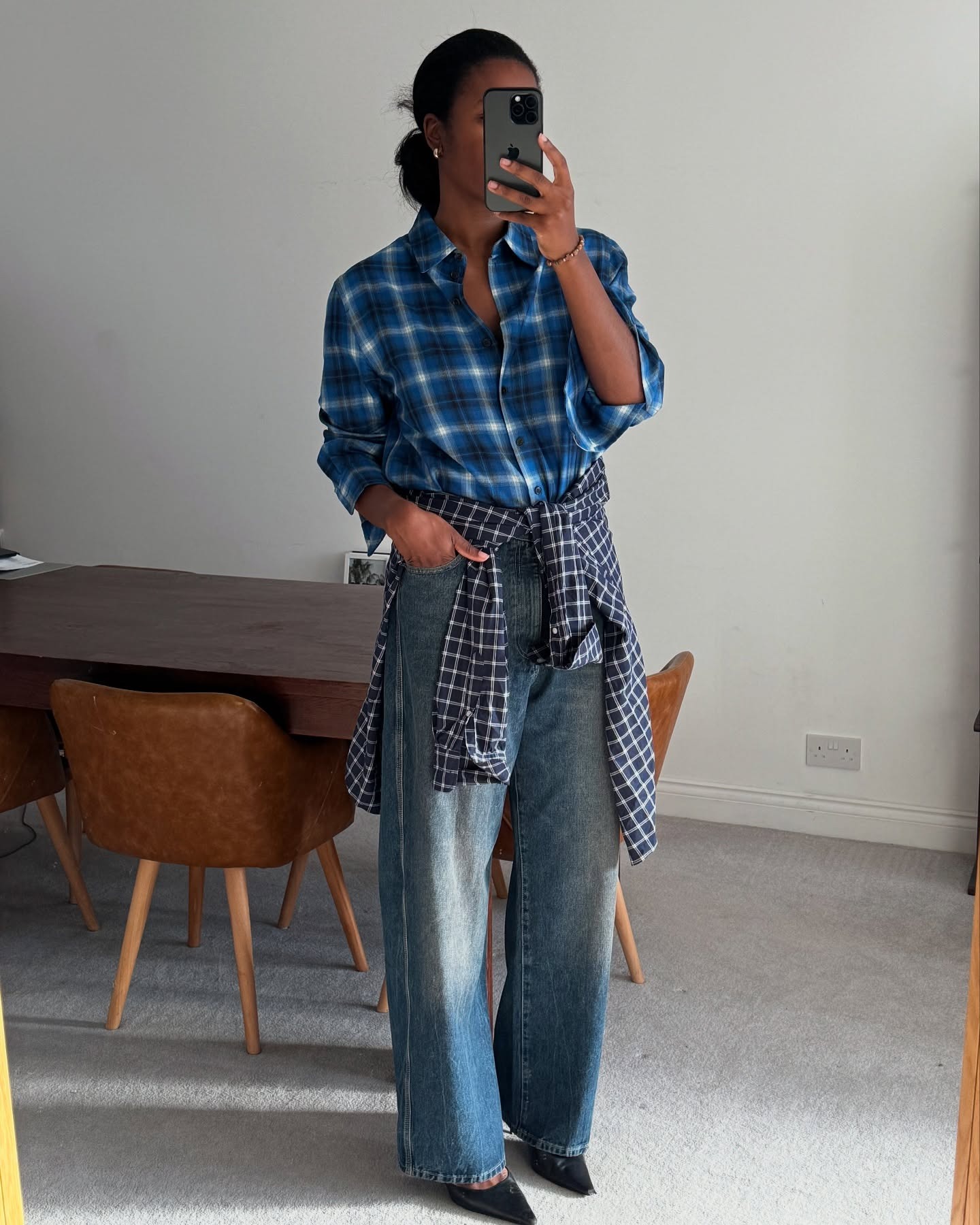Influencer Marilyn is in a plaid button-down shirt with another plaid button-down tied around their jeans.