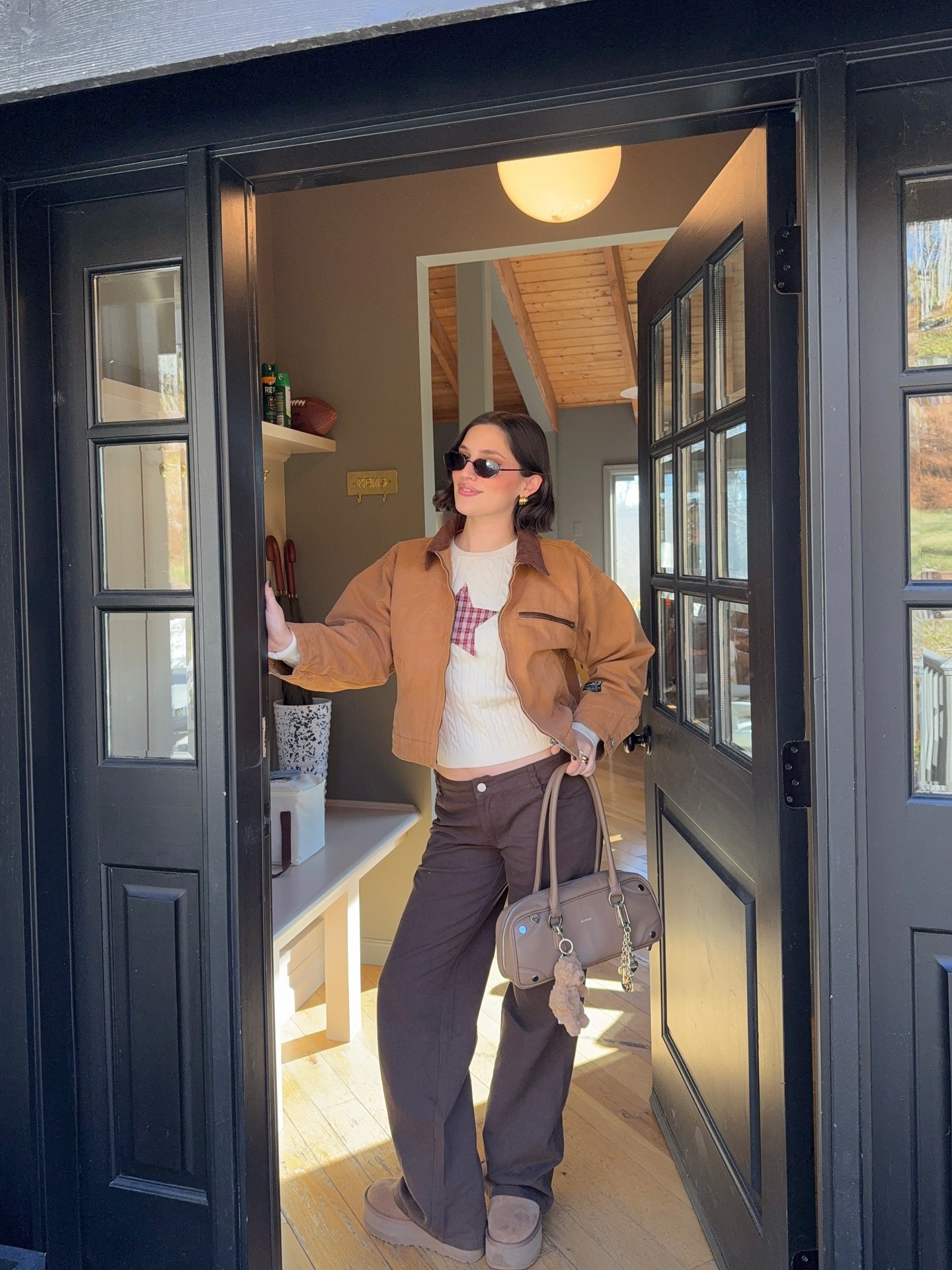 Influencer @ariannabaq wears brown jeans with a beige printed jumper, a brown canvas jacket and brown platform sheepskin boots.