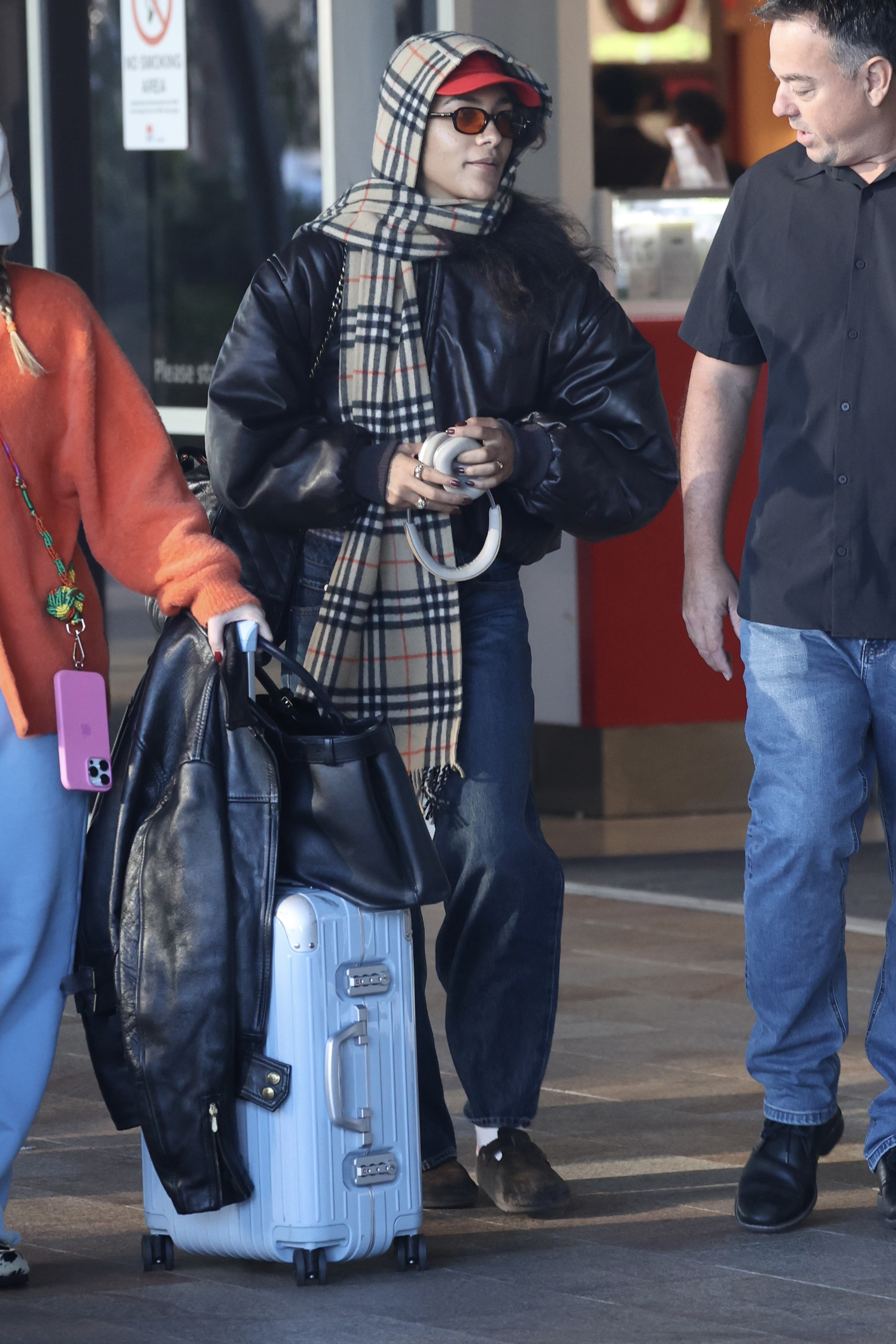 An image of Olivia Rodrigo wearing a leather bomber jacket and barrel-leg jeans to the airport.
