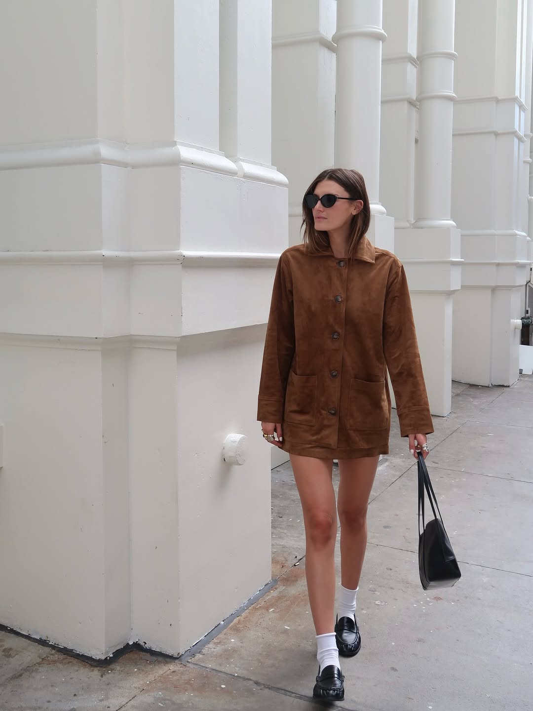 Coco Schiffer wearing a suede jacket with white socks and black ruched loafers