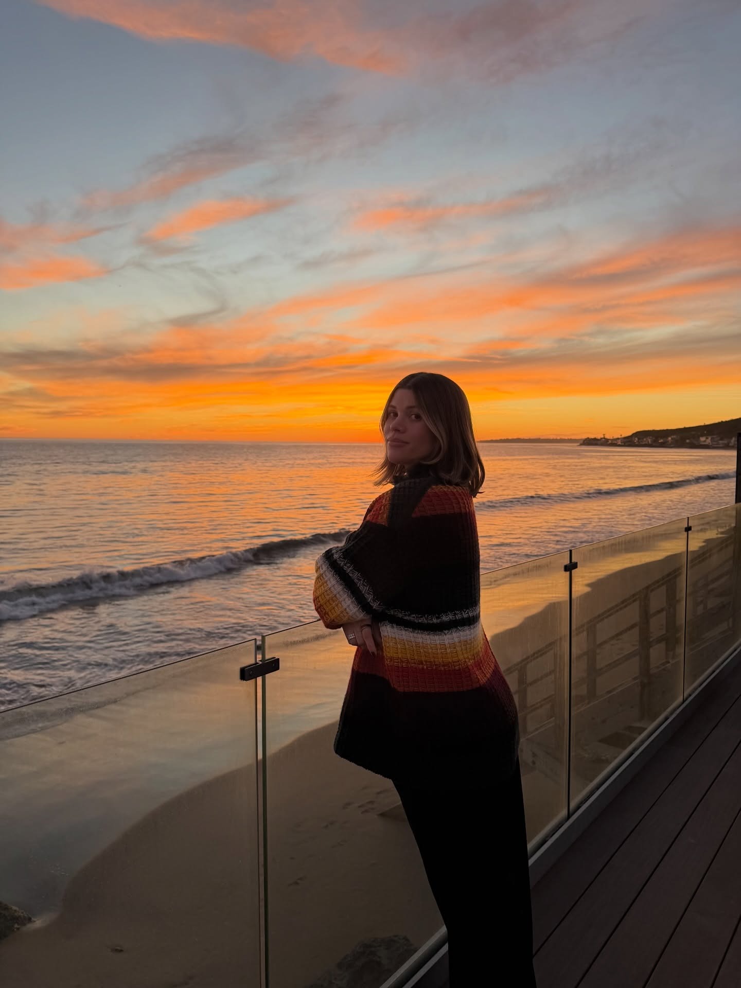 Sofia wears a stripe cashmere sweater with black pants.