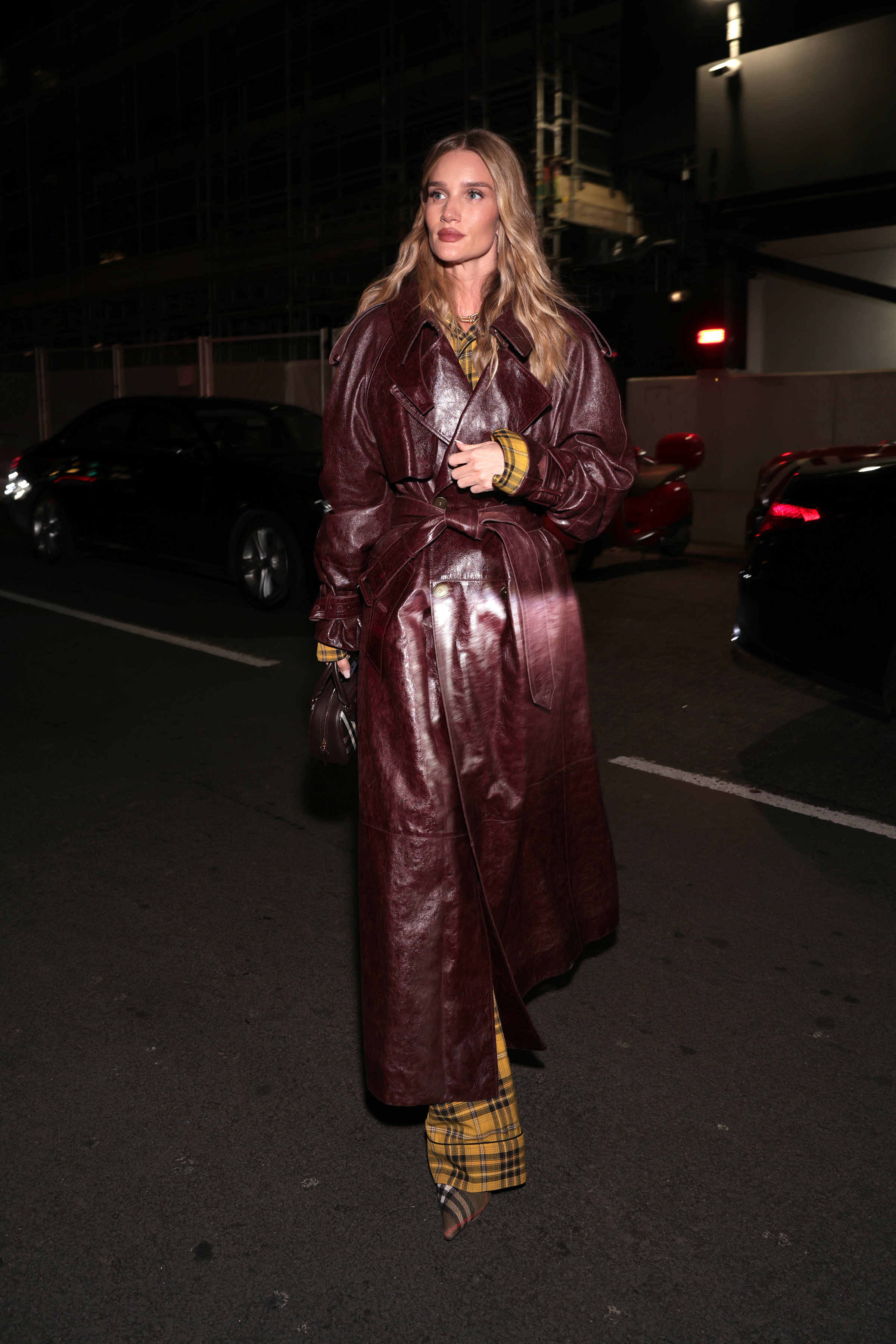Rosie wears a burgundy leather trench coat with yellow burburry pants and burberry pumps.