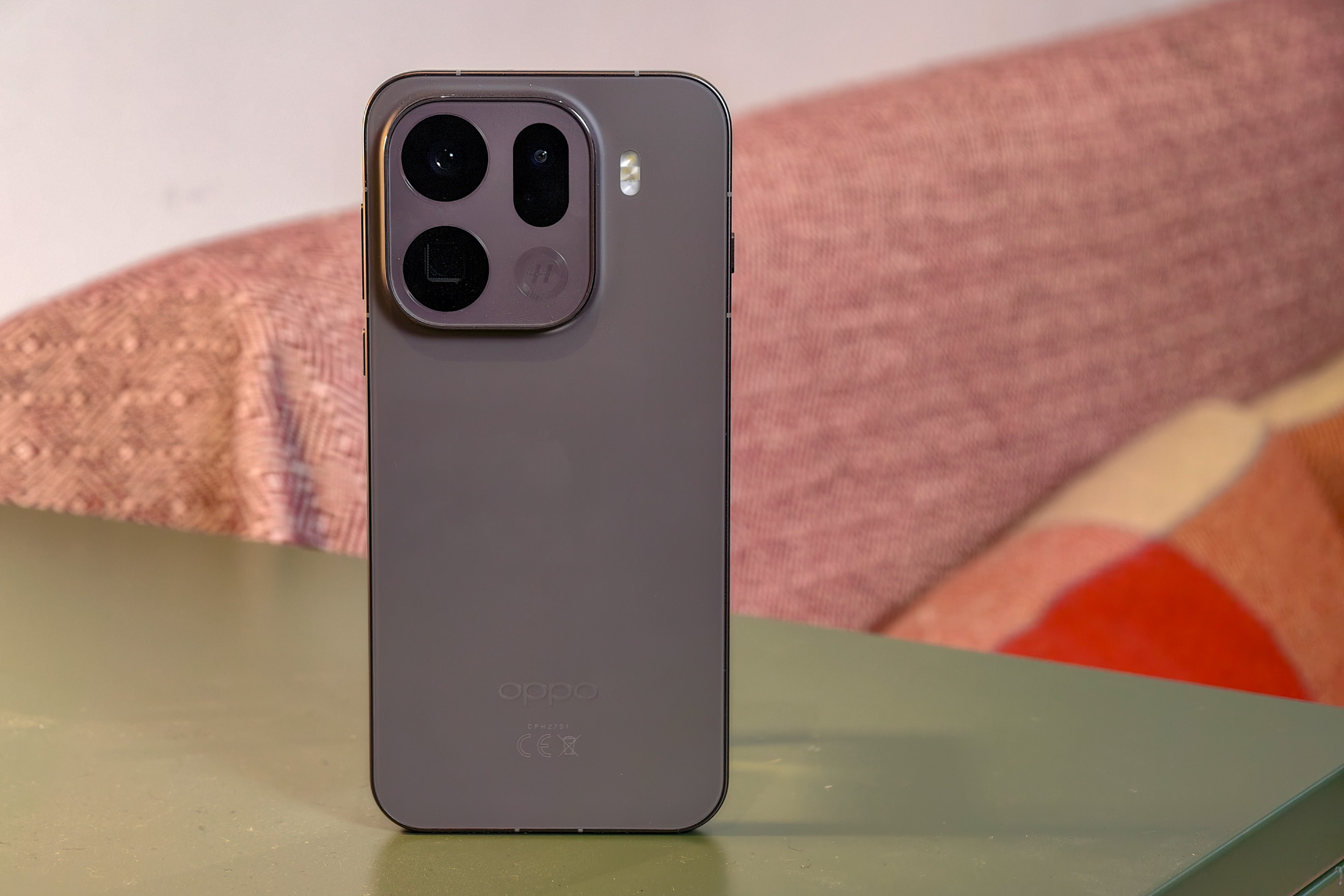 Oppo Find X9 Pro resting on a green table in front of a sofa