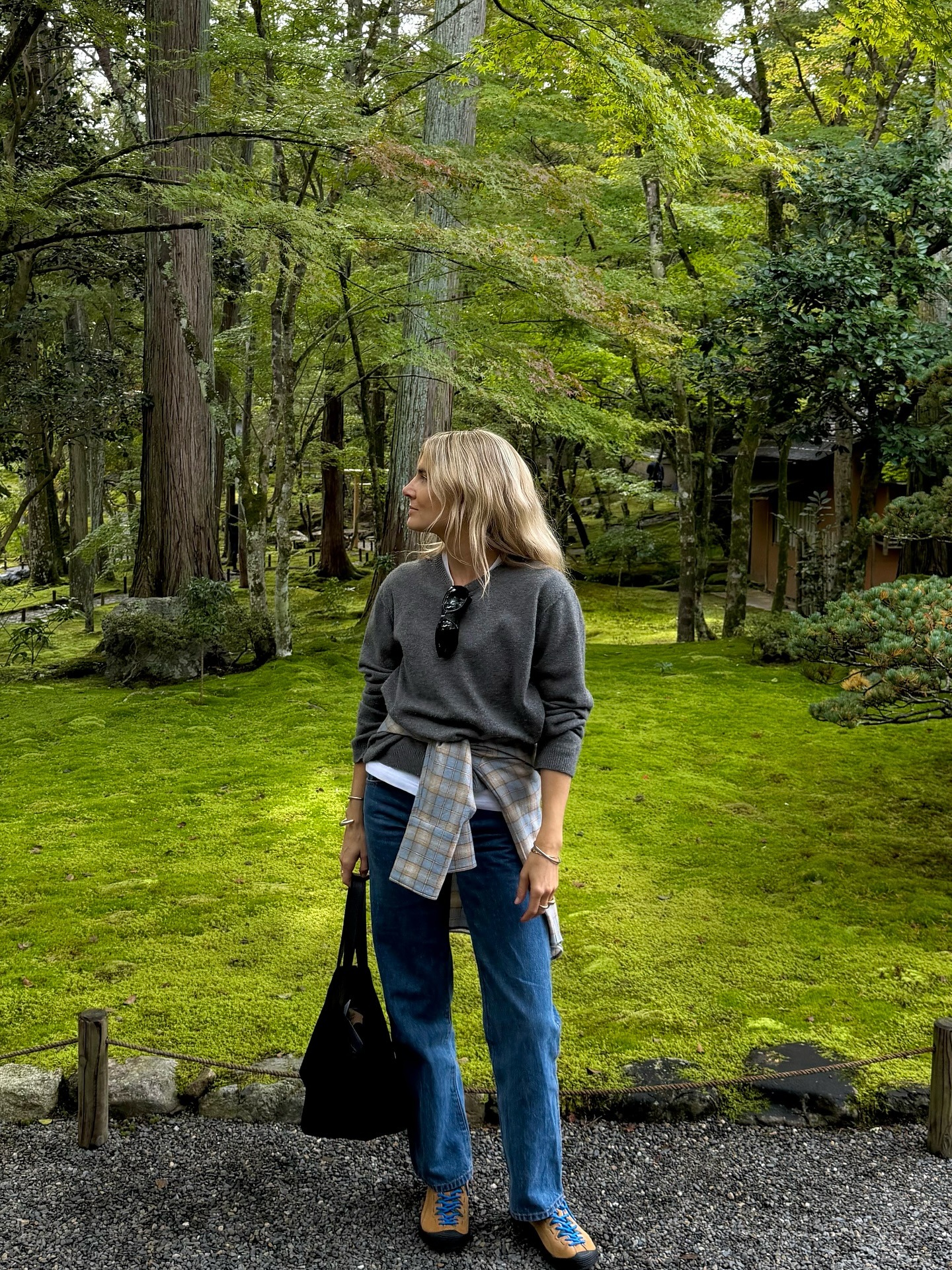 Fashion person Lucy Williams, @lucywilliams02 wears a leather trainer outfit 2026. She wears jeans a waisted shirt and a v neck jumper.