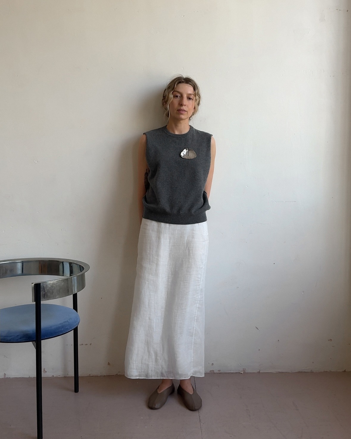 Influencer @brittanybathgate wears a silver brooch with a grey sleeveless knit, a white linen skirt and soft ballet flats.