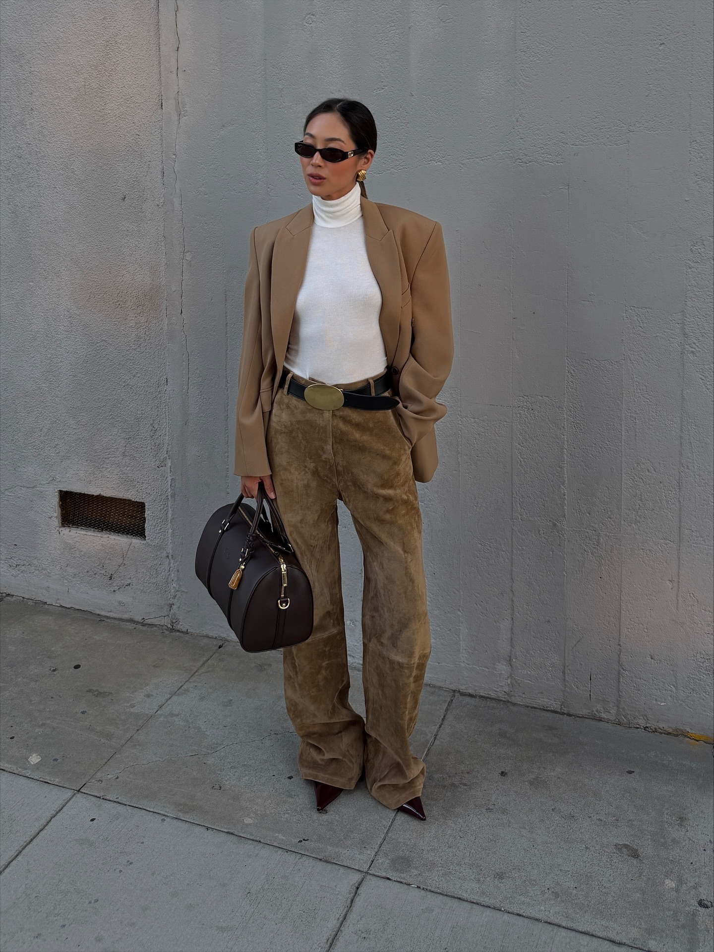 Aimee Song in wide-leg brown suede pants, brown blazer, and white turtleneck.