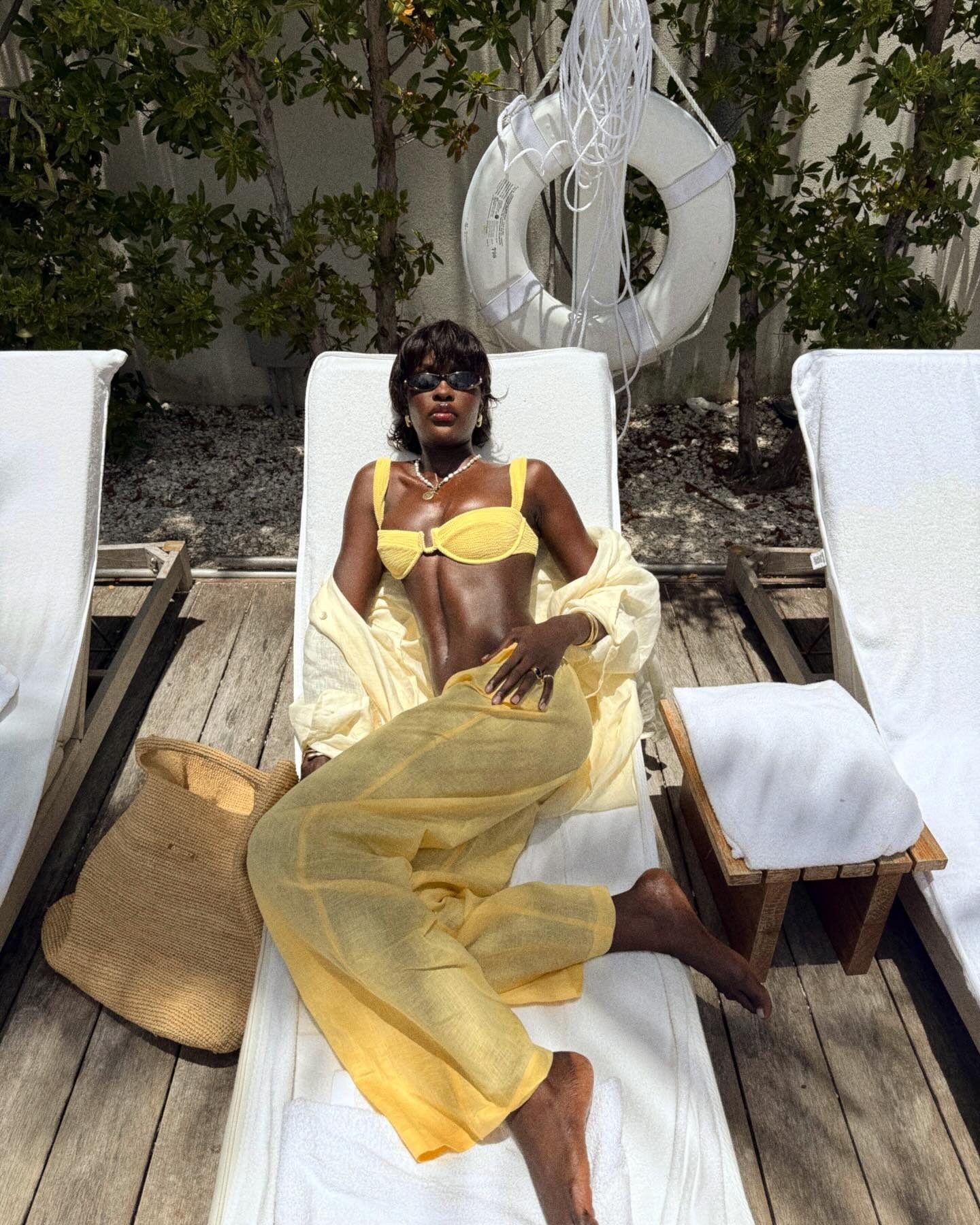 A woman wears a yellow bikini with yellow pants.