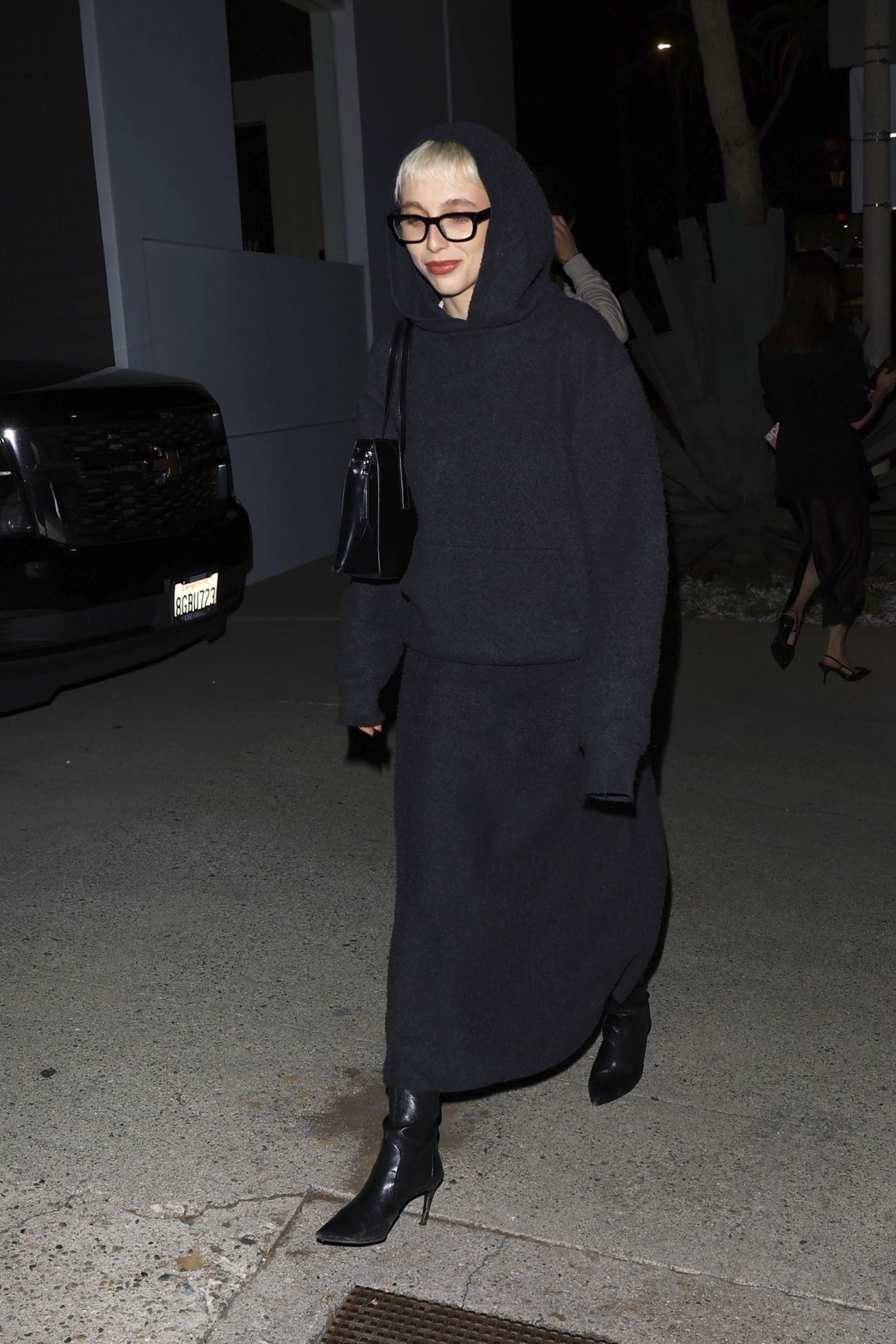 Emma Chamberlain wearing a gray knit set and slouchy black boots