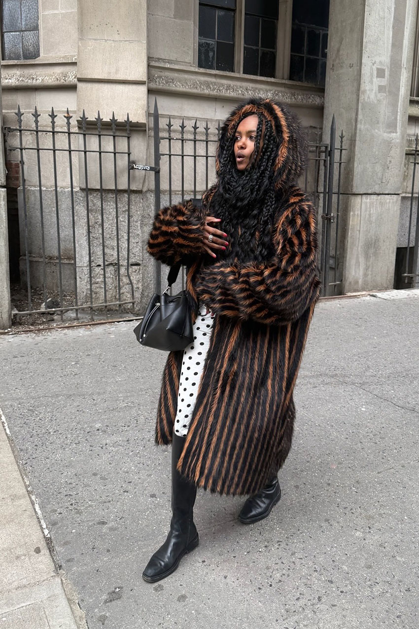 A woman wearing a brown fur coat and black knee-high boots