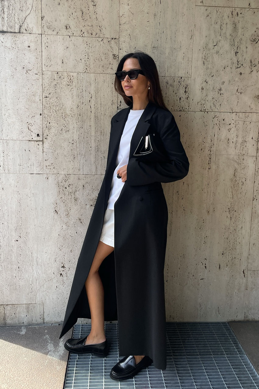 A woman wearing a black coat and flat leather loafers