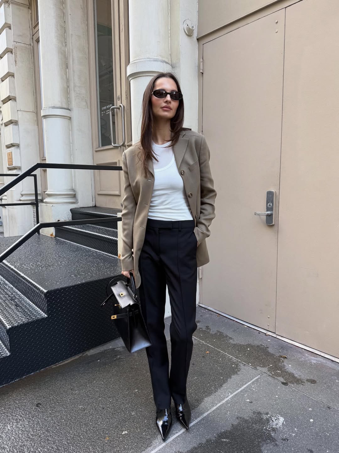 A woman wearing black pants with a beige blazer and leather boots.