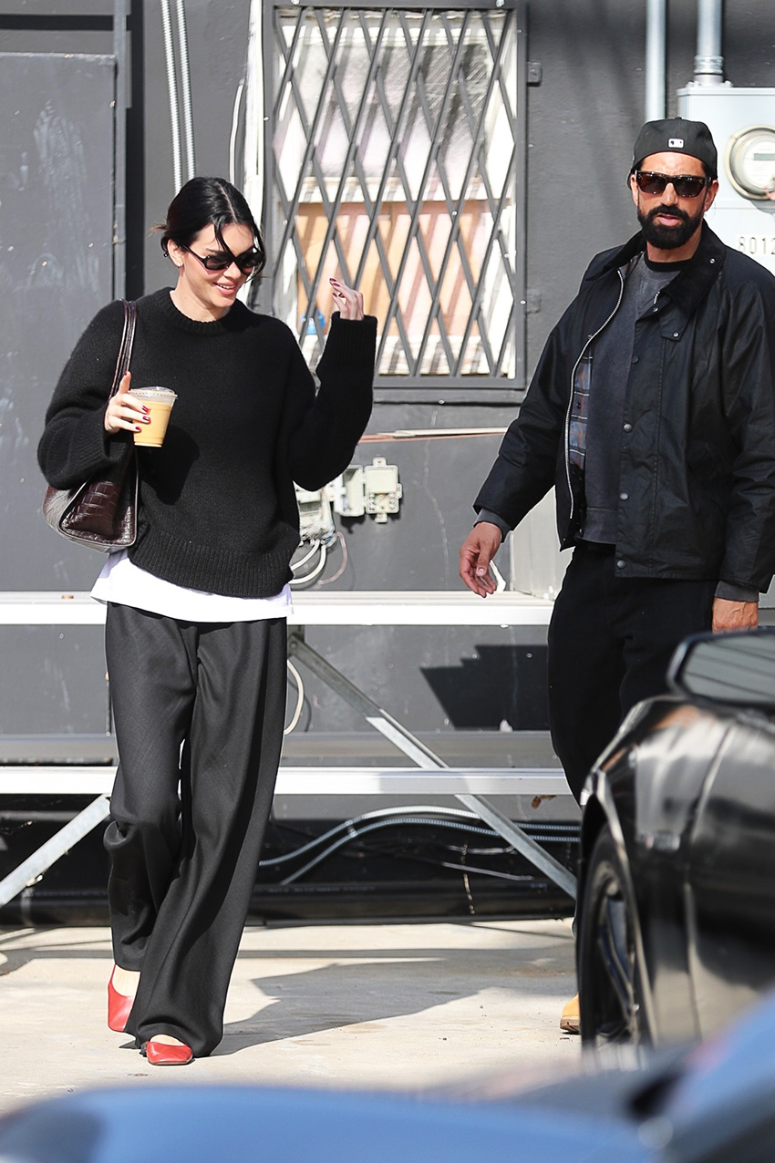 Kendall Jenner in Los Angeles wearing a black sweater, loose black pants, red The Row ballet flats, and a croc shoulder bag