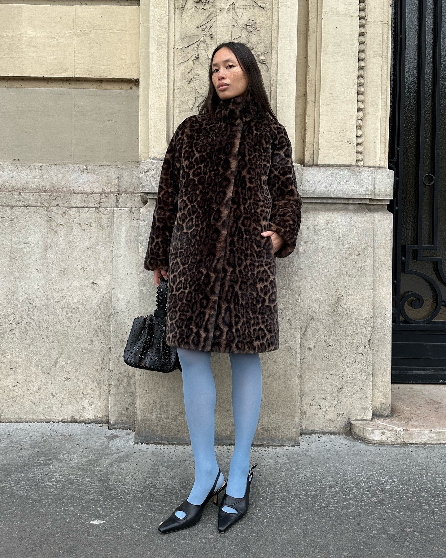 Influencer @vikilefevre wears blue tights with black pointed-toe slingbacks and a leopard print coat.