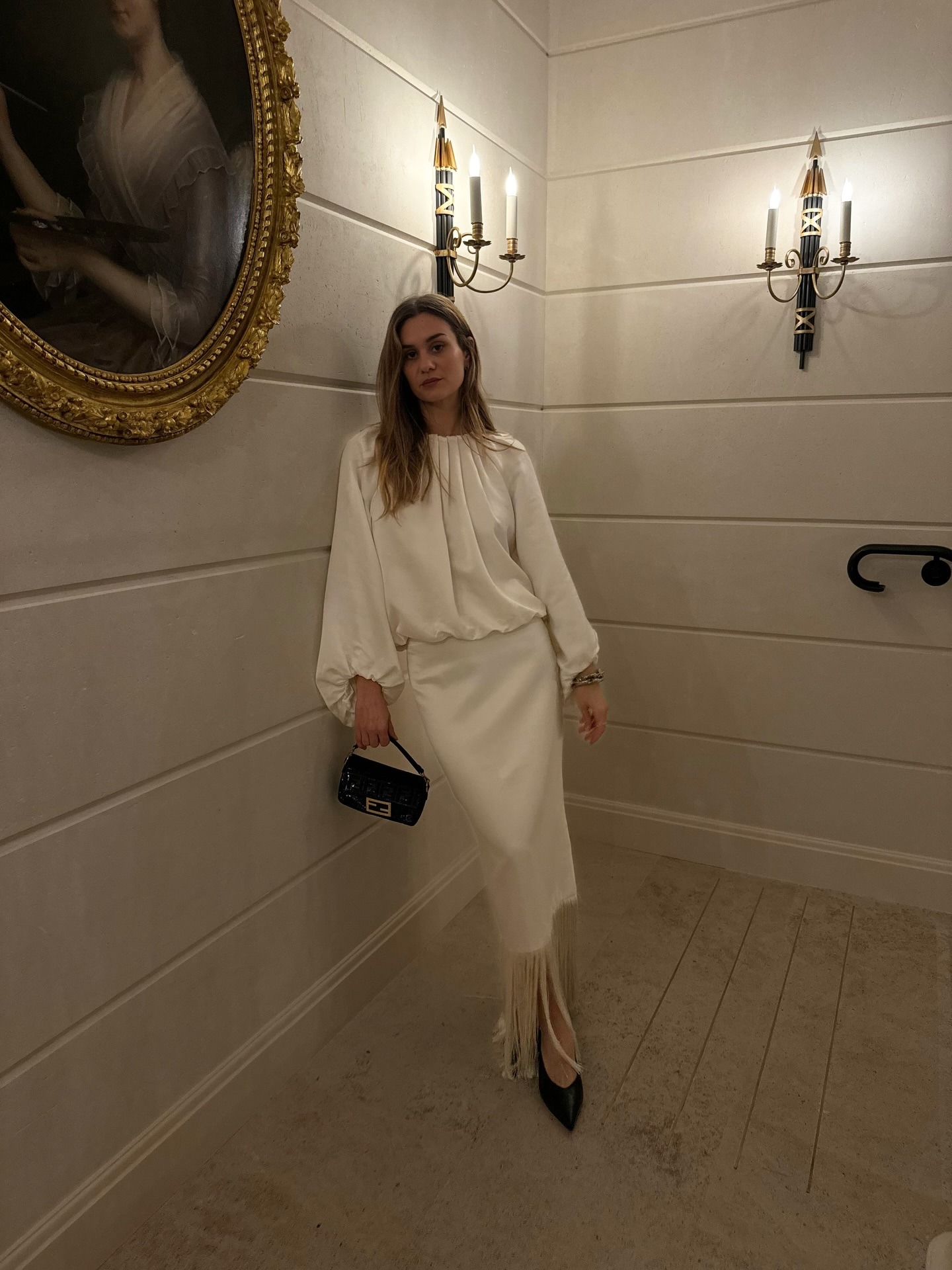 Influencer @annelauremais wears a satin dress with pointed-toe heels and a black clutch bag.