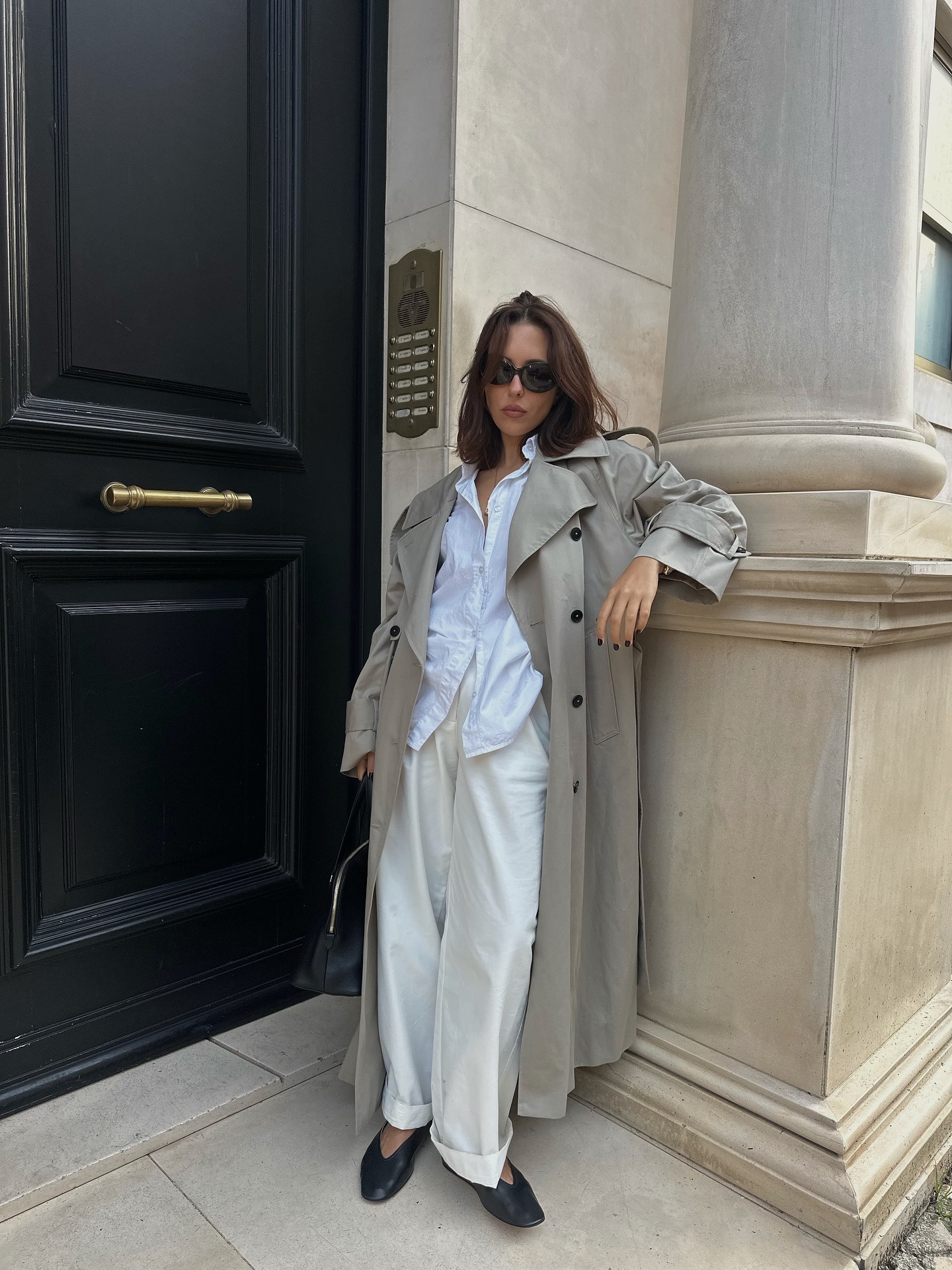 Influencer @&amp;#8203;&amp;#8203;deborabrosa wears white trousers with a grey trench coat and black soft leather ballet pumps.