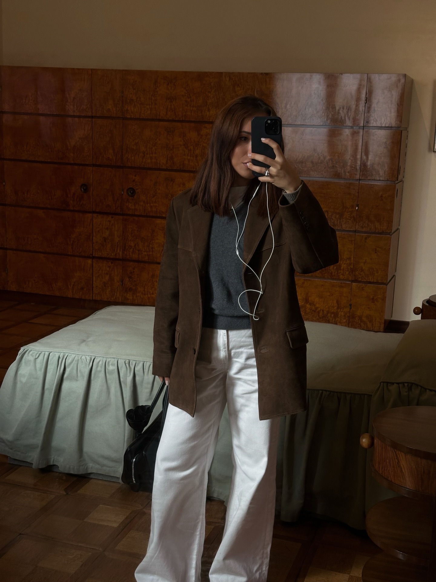 An image of @deborabrosa wearing white jeans, a palette cleansing hue that&#039;s one of the biggest 2026 jean trends, with a suede jacket and grey jumper.