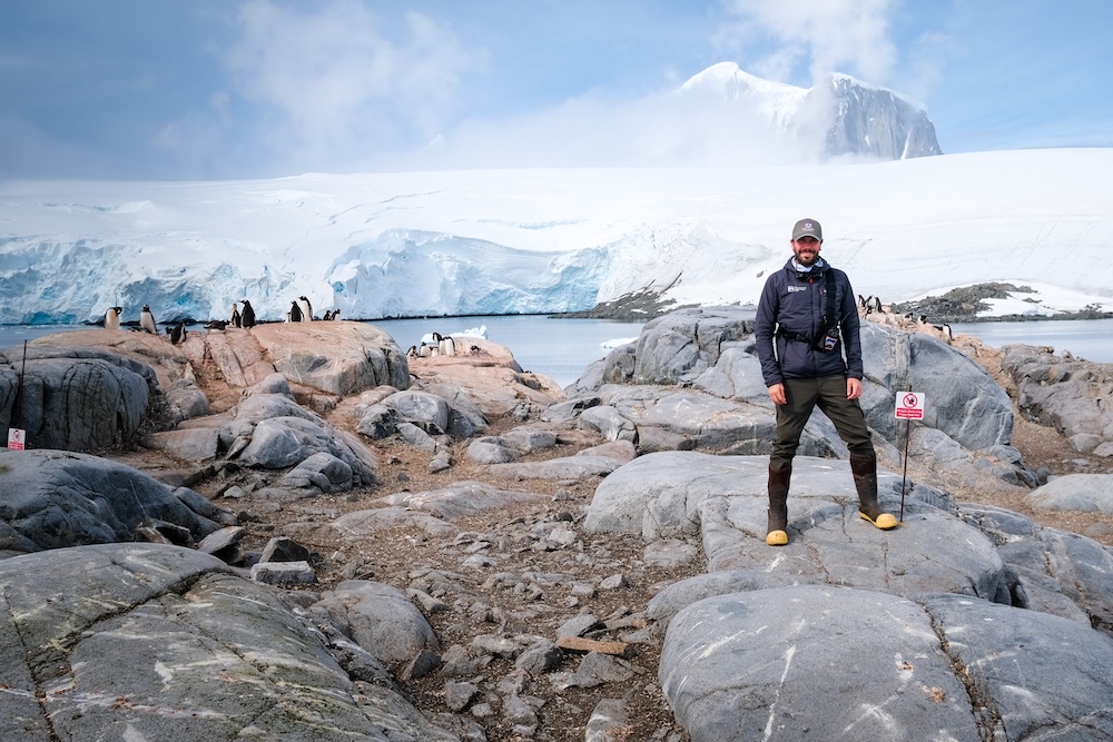 Peter with penguins in the background at the Antarctic destination of Port Lockroy