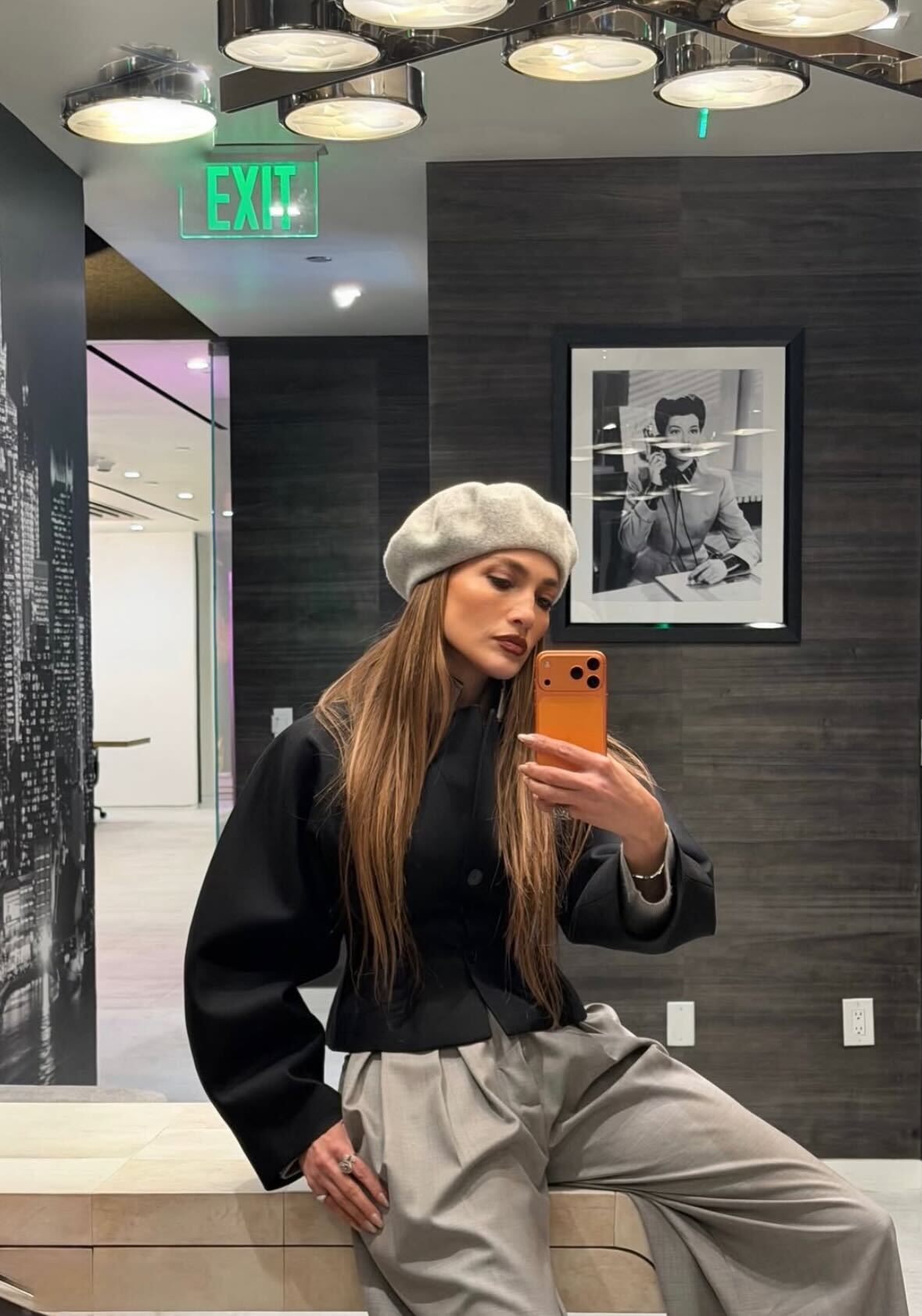 J.lo wears a grey beret, black top, and light grey trousers.